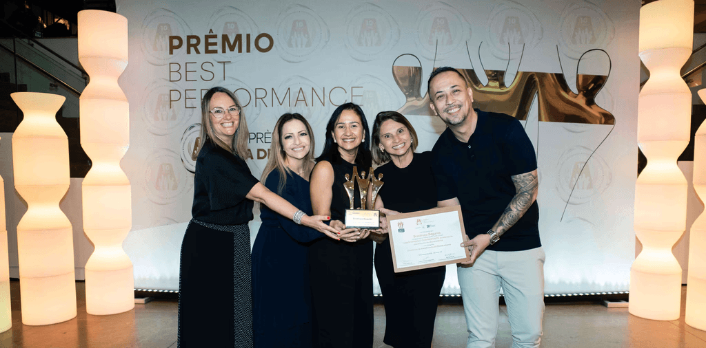 Executivos da Bradesco Seguros posando com troféu ouro e certificado no palco do Prêmio Best Performance 2025