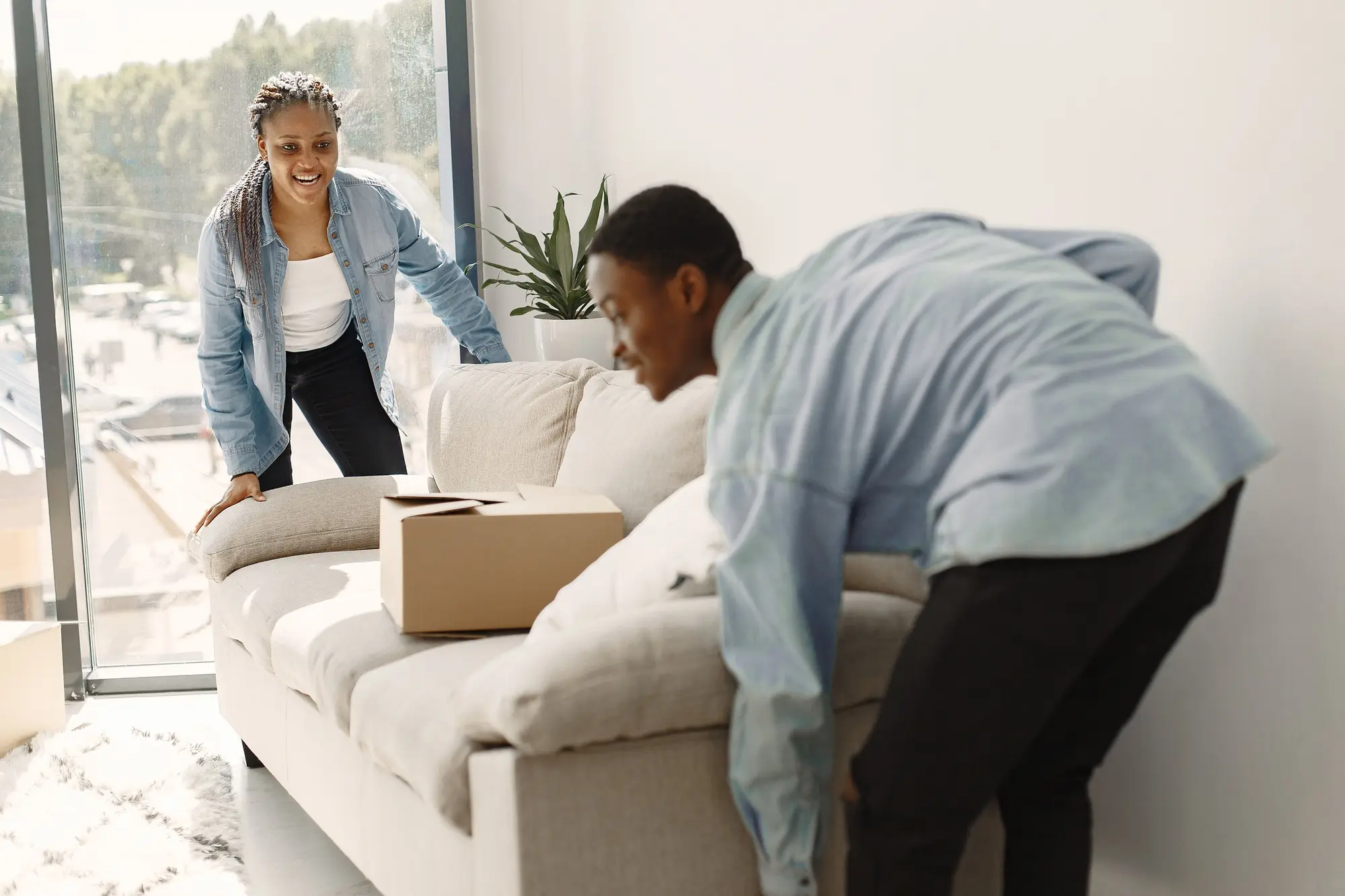 Two people moving a couch in a house.