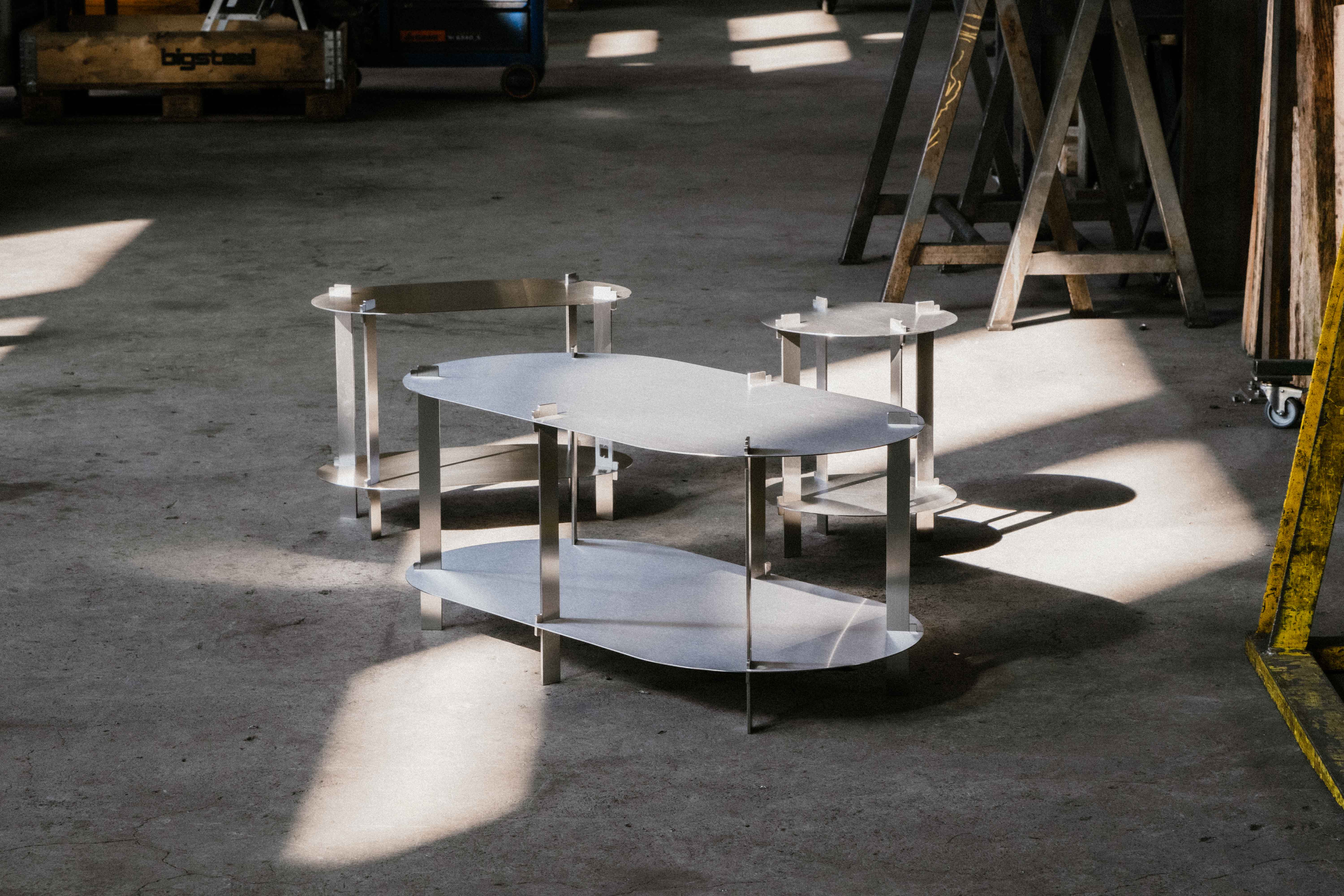 Three steel Coffee Tables in a workshop, sun shining on the scene