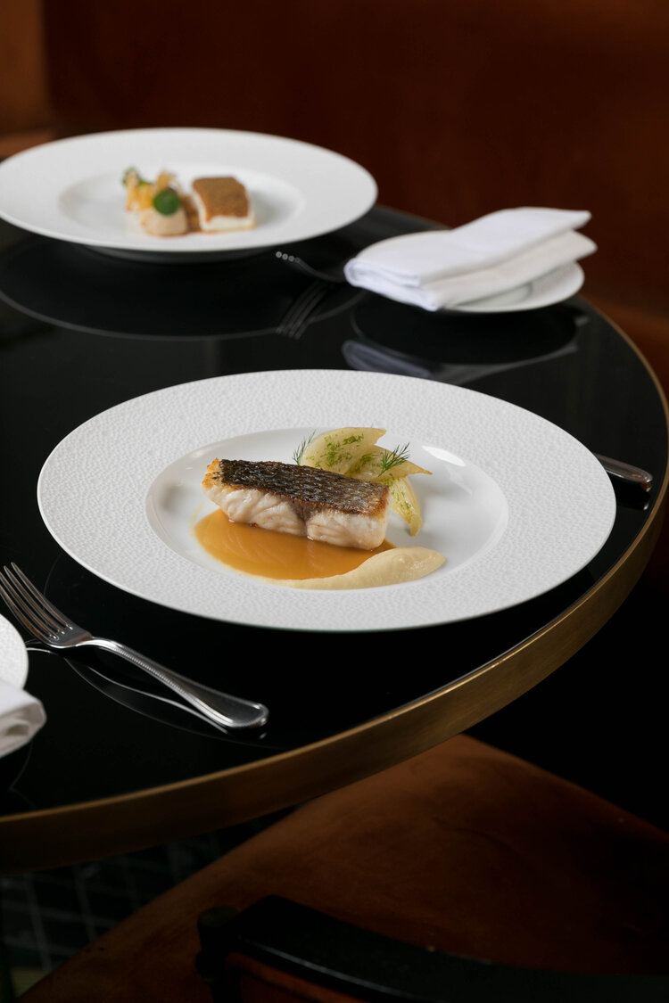 A fine dining dish elegantly plated on a white plate in a sophisticated restaurant setting.