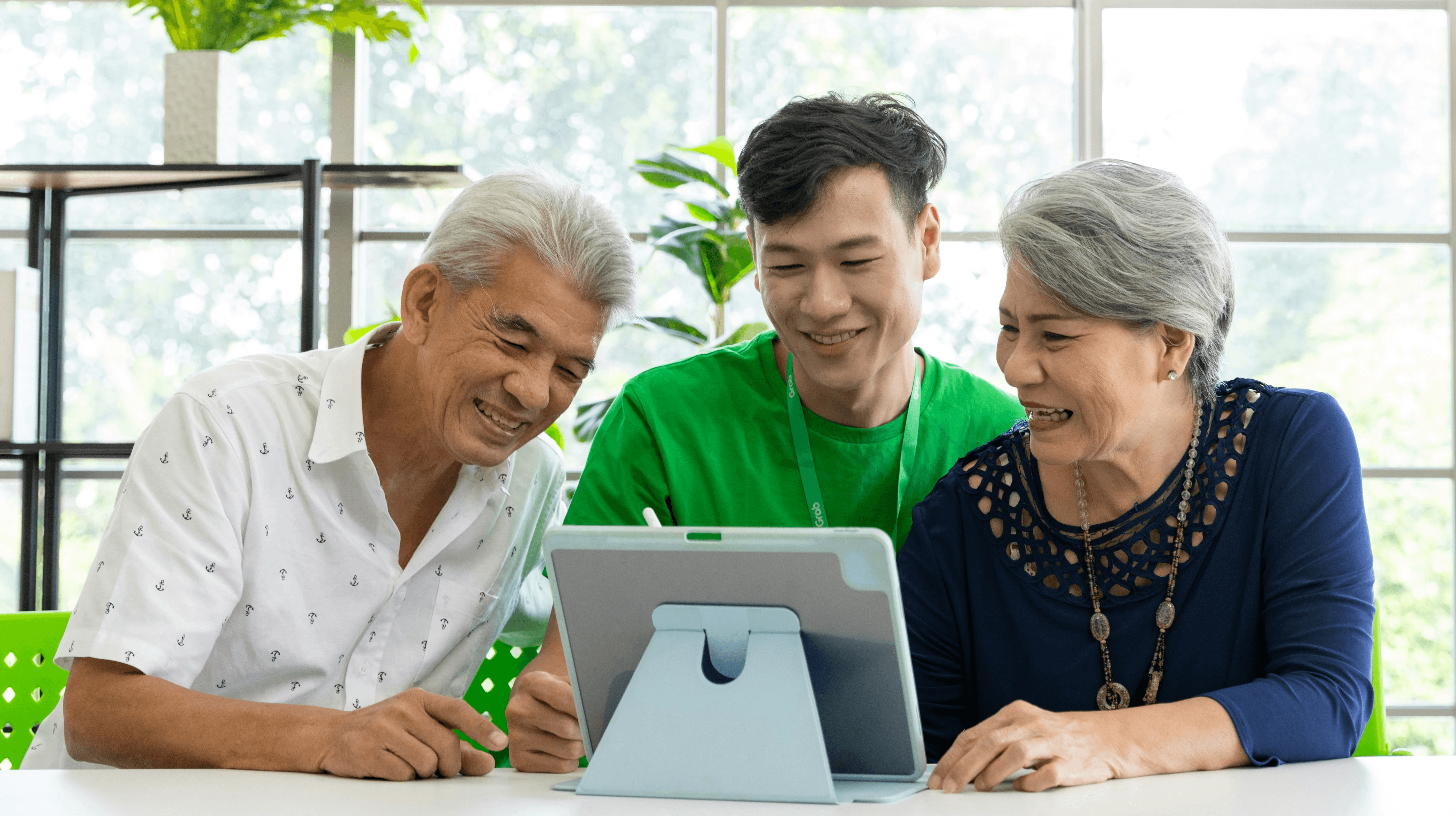 elderly couple and younger man look at computer screen