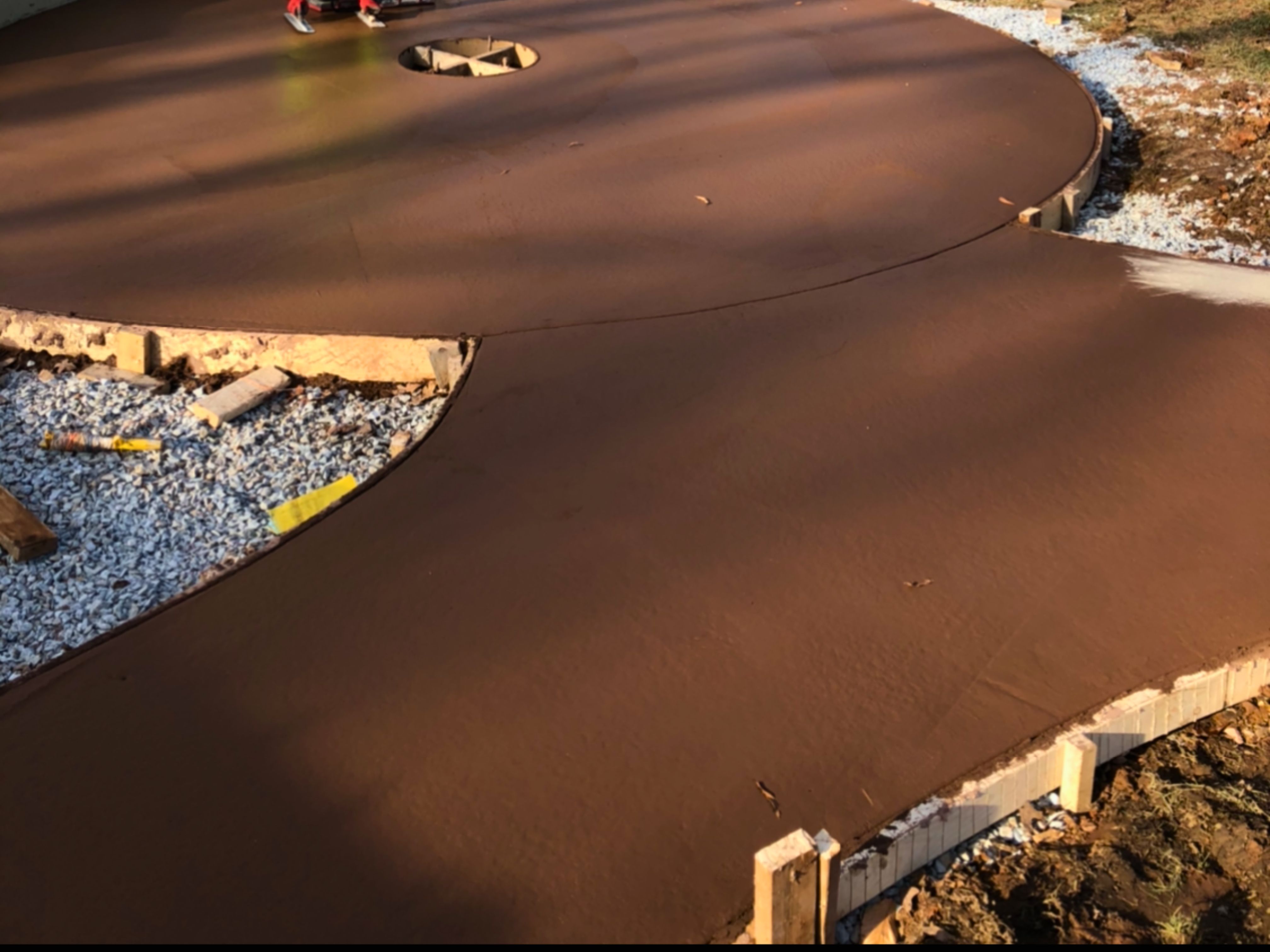 Concrete crew forming and pouring the curved stamped walkway and round fire pit patio in a Durham, NC backyard.