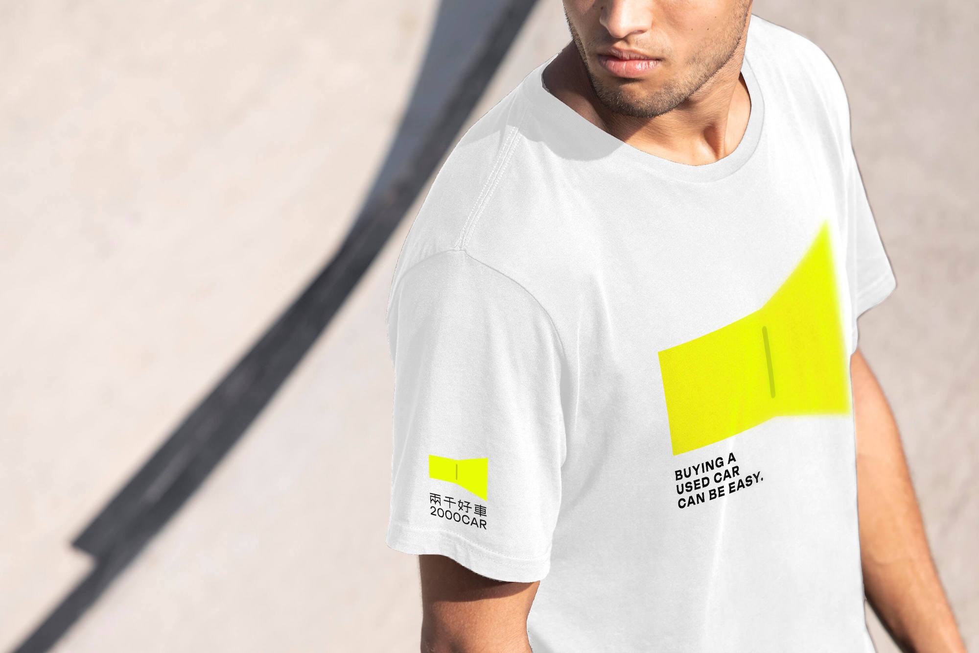這張圖像展示了兩千好車的品牌T恤,白色T恤上印有兩千好車的螢光黃色識別和購買二手車的英語標語。