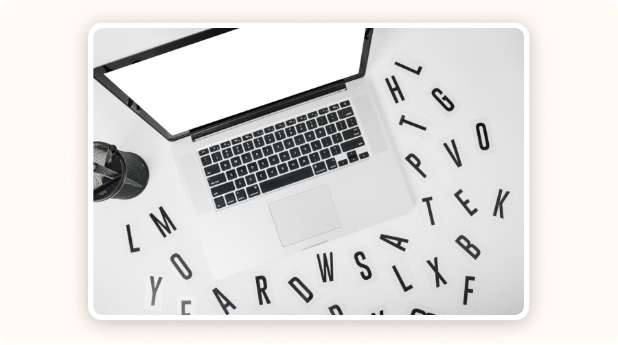 Laptop surrounded by scattered letters — a visual of ad copy analysis and SEO keyword review.