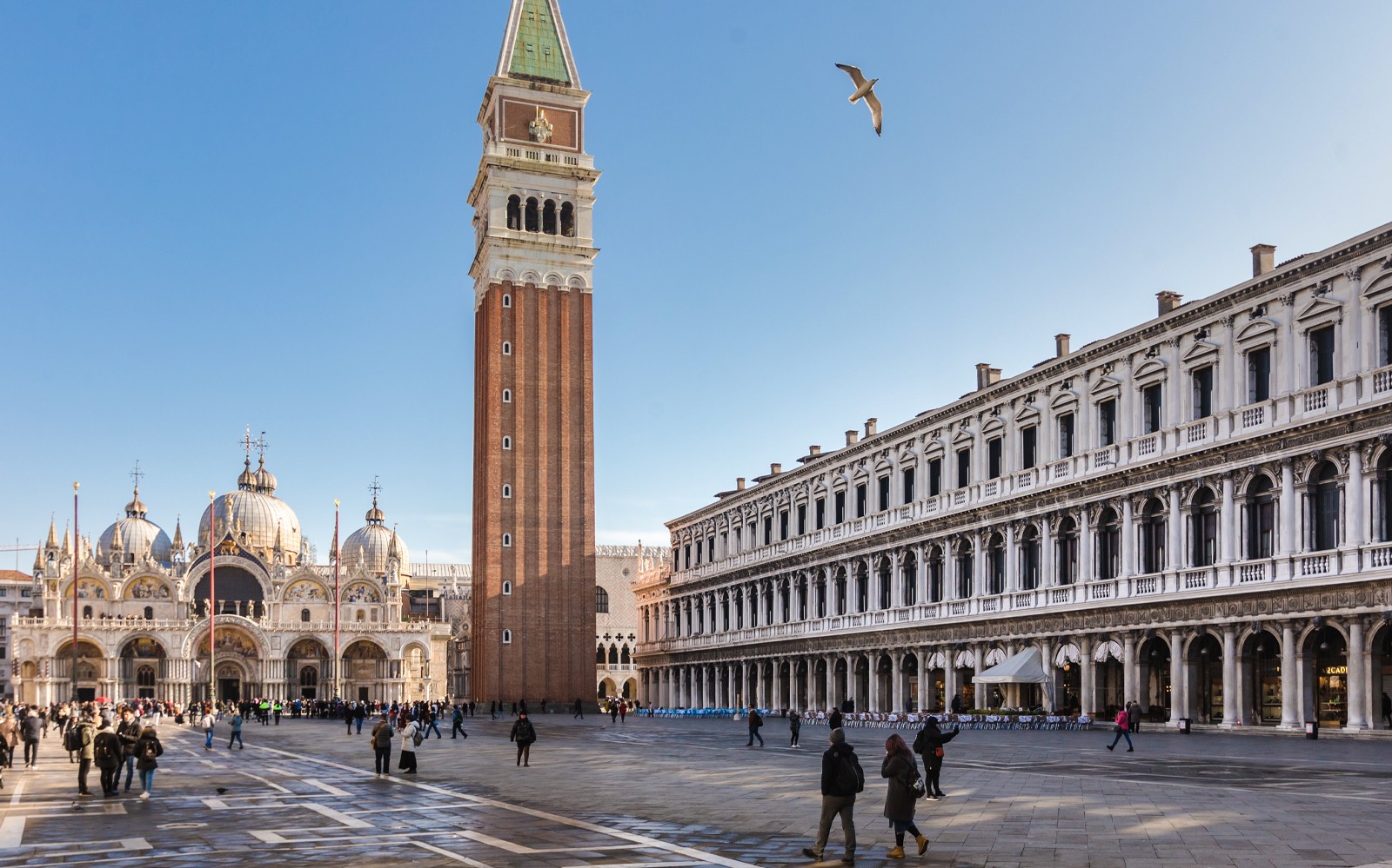 Gondoltur på en kanal i Venedig med turister og historiske bygninger i udsigt.
