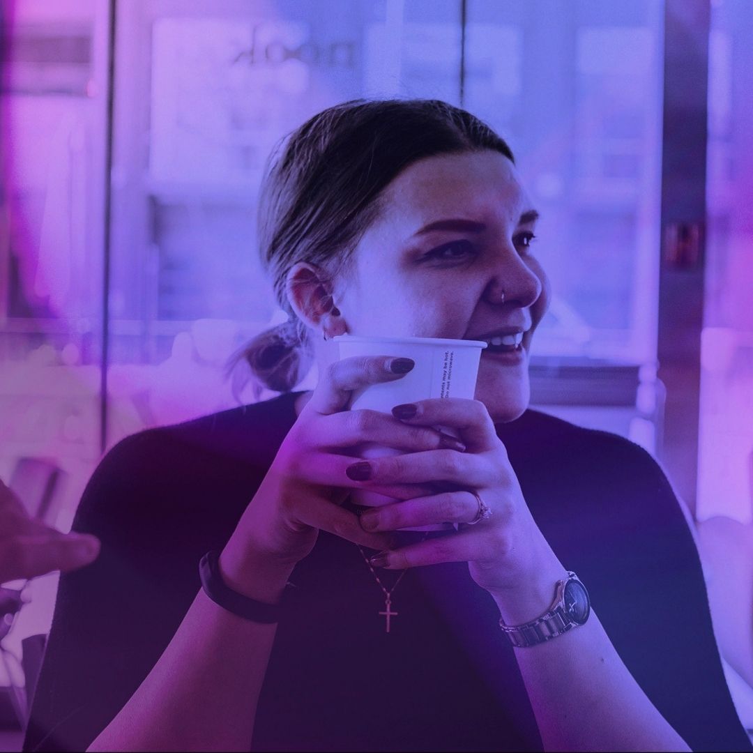 A woman looks to her left while holding a coffee