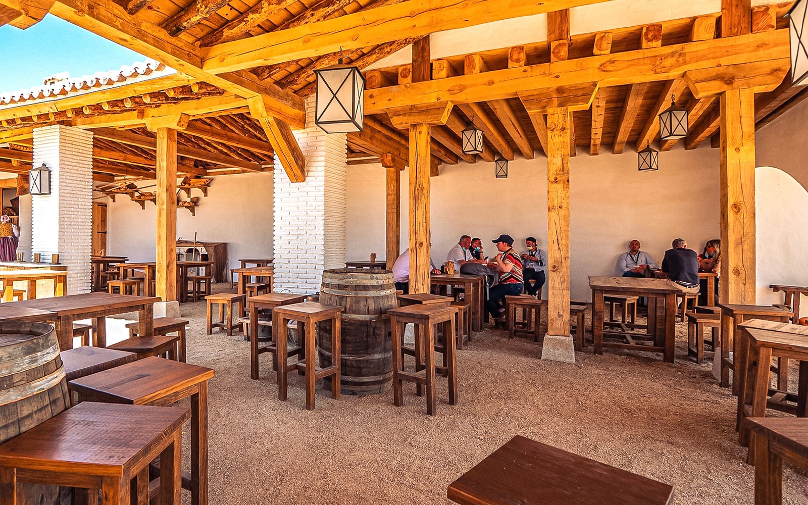 Outdoor dining area with wooden tables and people at Puy du Fou Park.
