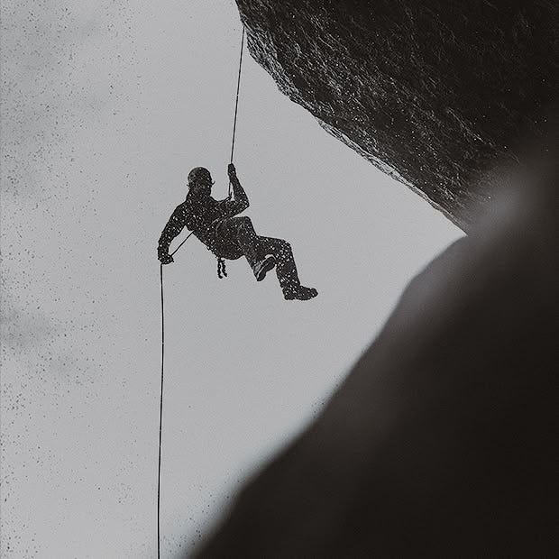 This may contain: a man climbing up the side of a cliff with a rope attached to his feet