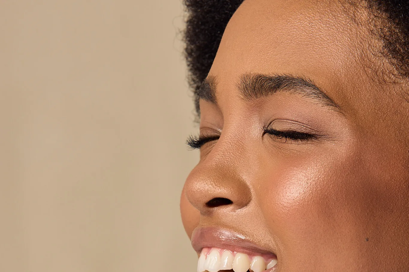 A woman laughs with her eyes closed as she lifts a Sēkret capsule to her lips