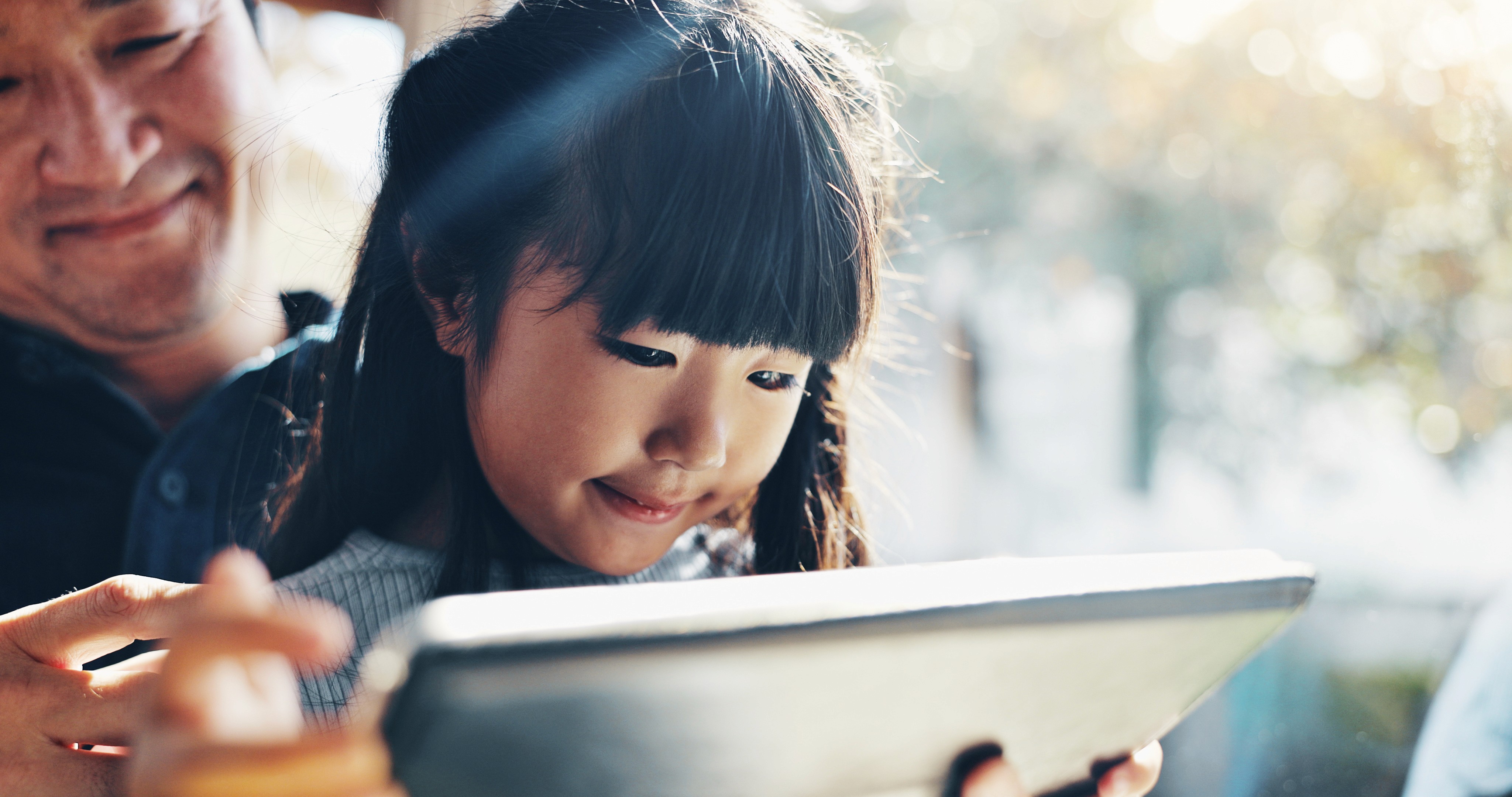 Parent and child studying together with tablet at home, engaged in learning