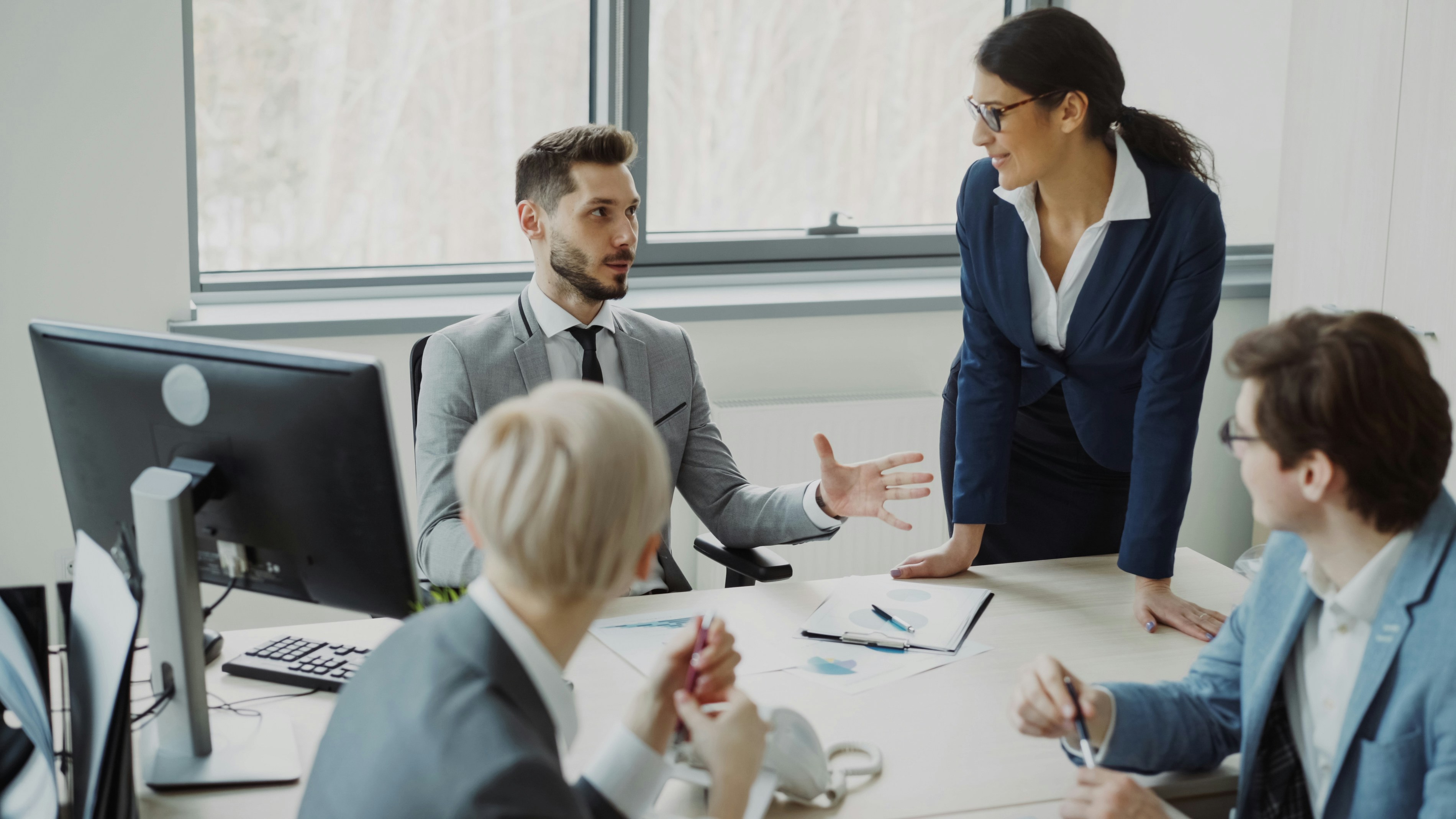 Business team in a meeting discussing documents and strategy around an office conference table.