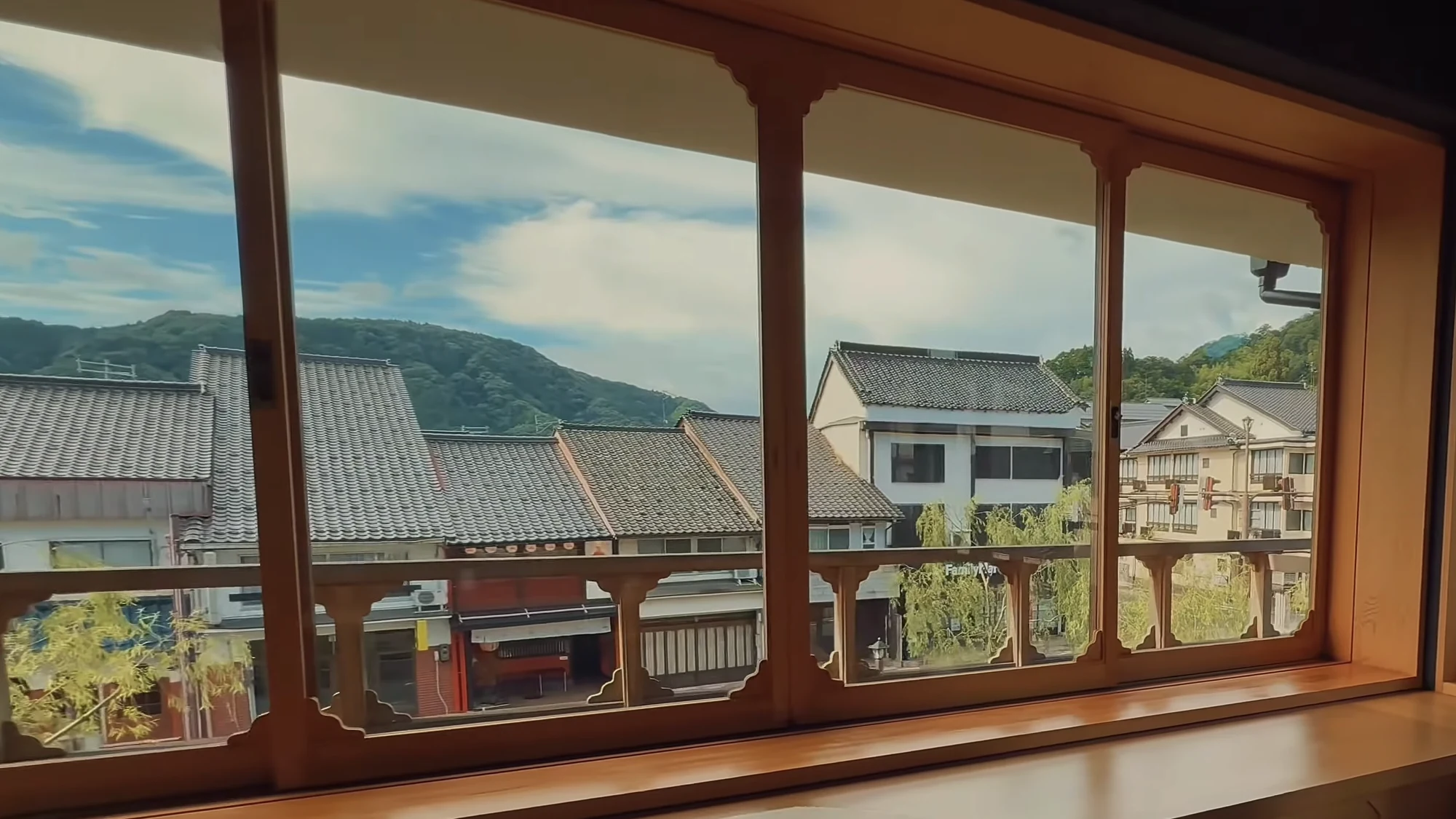 The Kinosaki street framed from inside a timber inn window in summer.