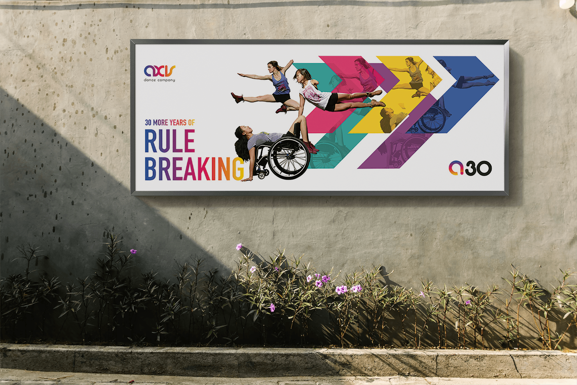 A large outdoor banner poster for AXIS Dance Company's 30th Anniversary, three disabled dancers in motion are reflected in colorful chevron shapes behind them.