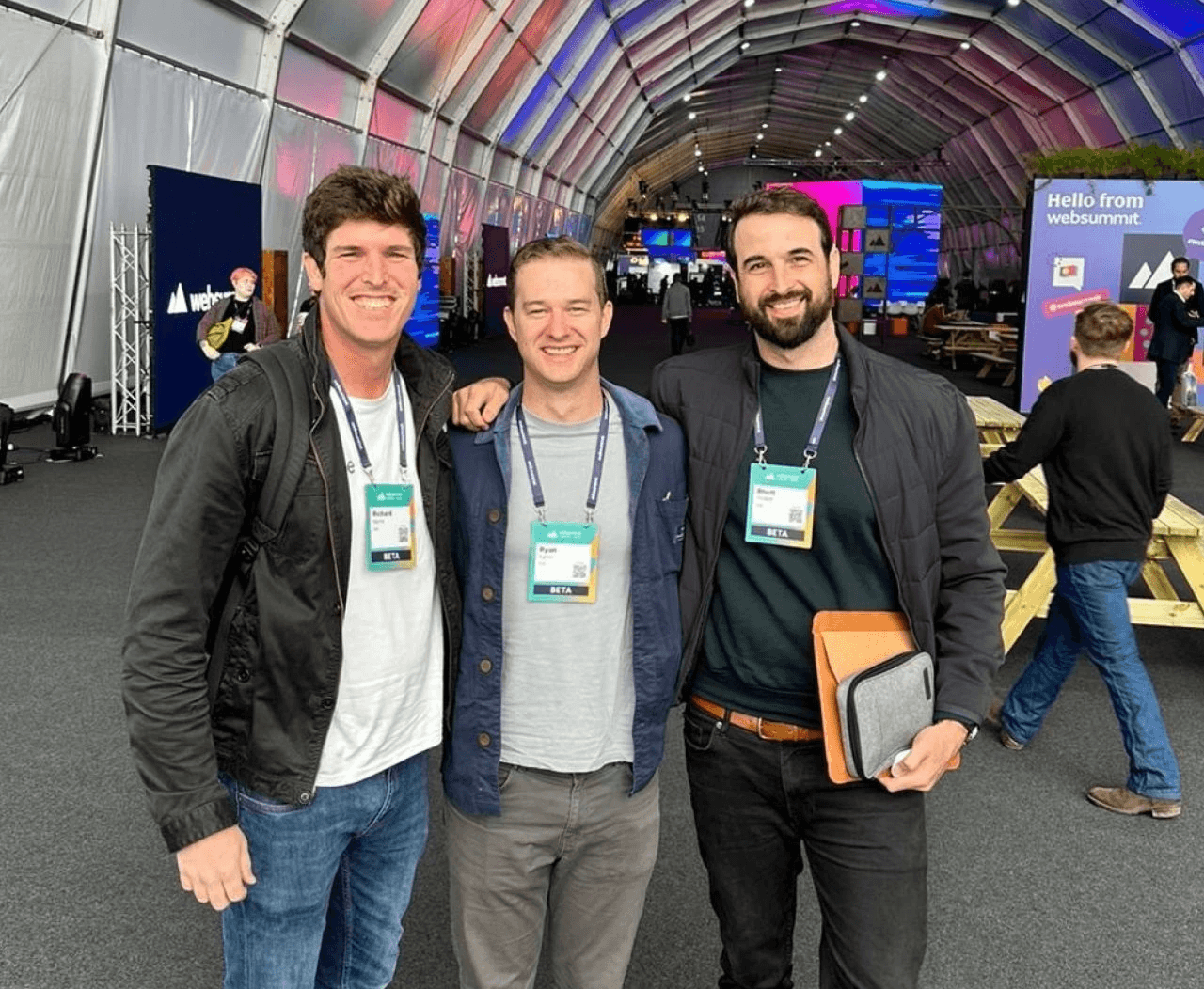 Cue founders with lanyards and badges at an event, standing close together for a photo.