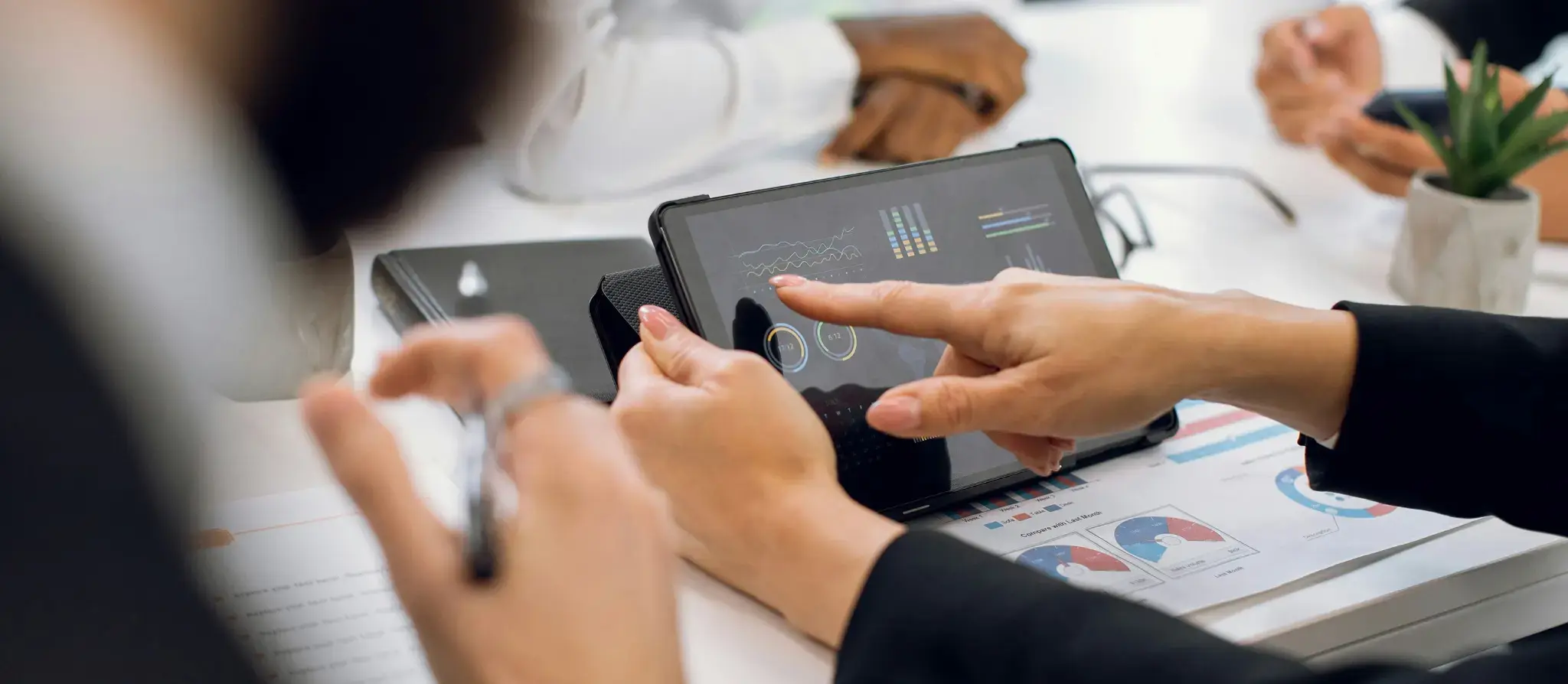 Woman pointing at a graph on a tablet screen during a meeting