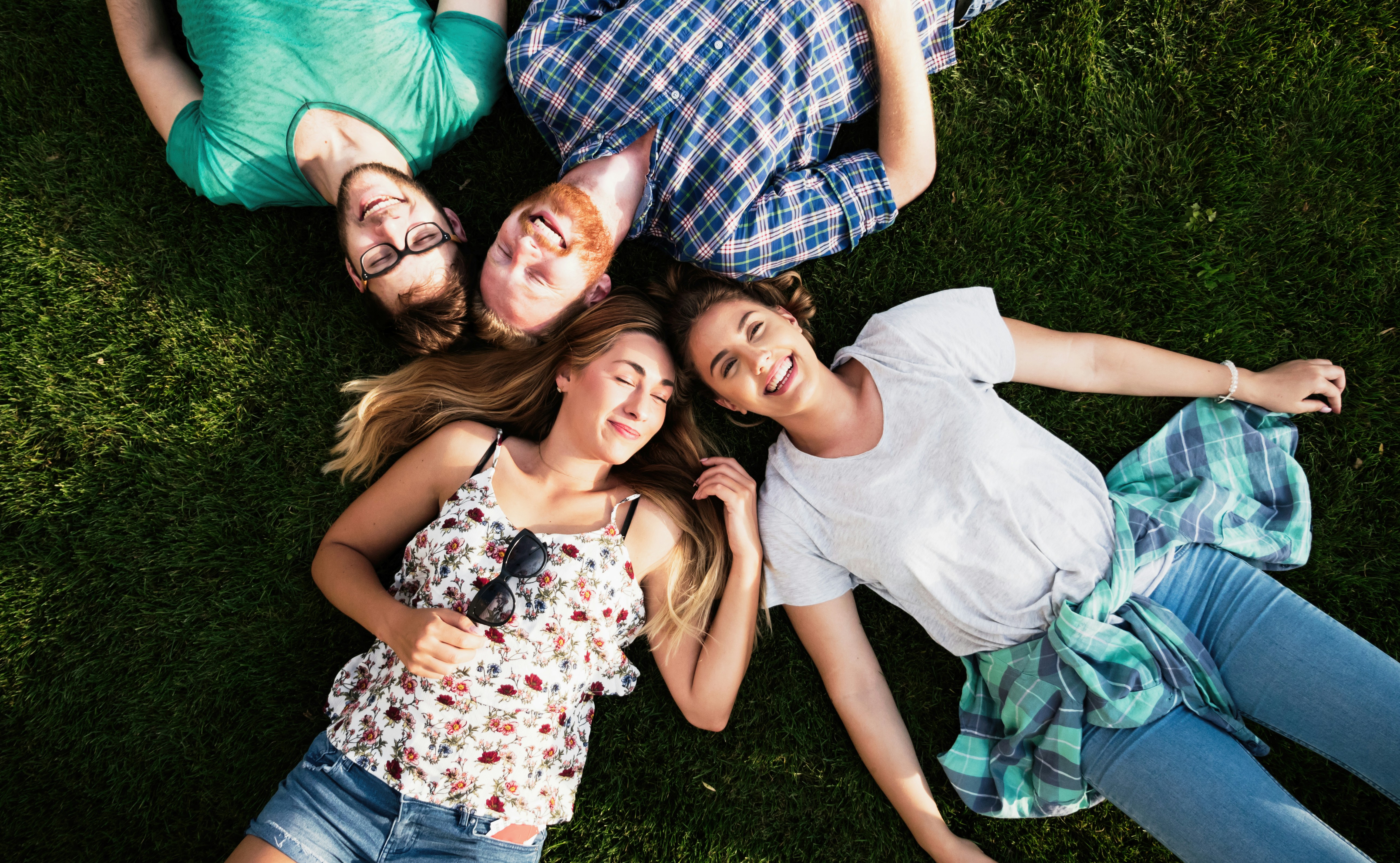 four teens lying on ground and looking up