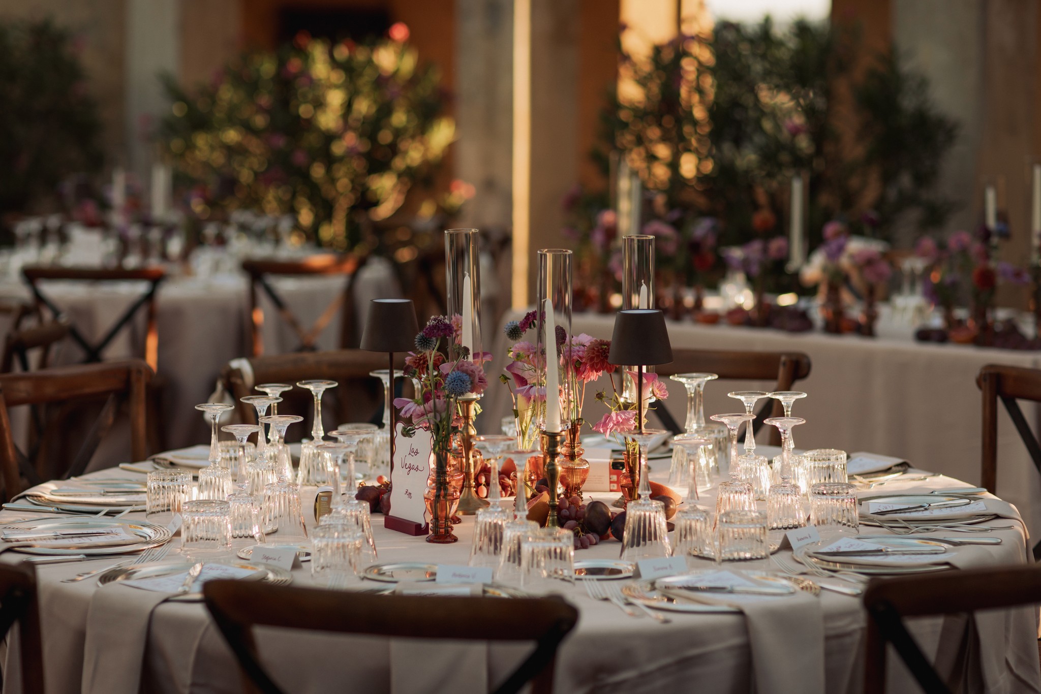 Tavolo rotondo addobbato con fiori e candele al ricevimento di matrimonio al Castello di Scipione, luce dorata al tramonto