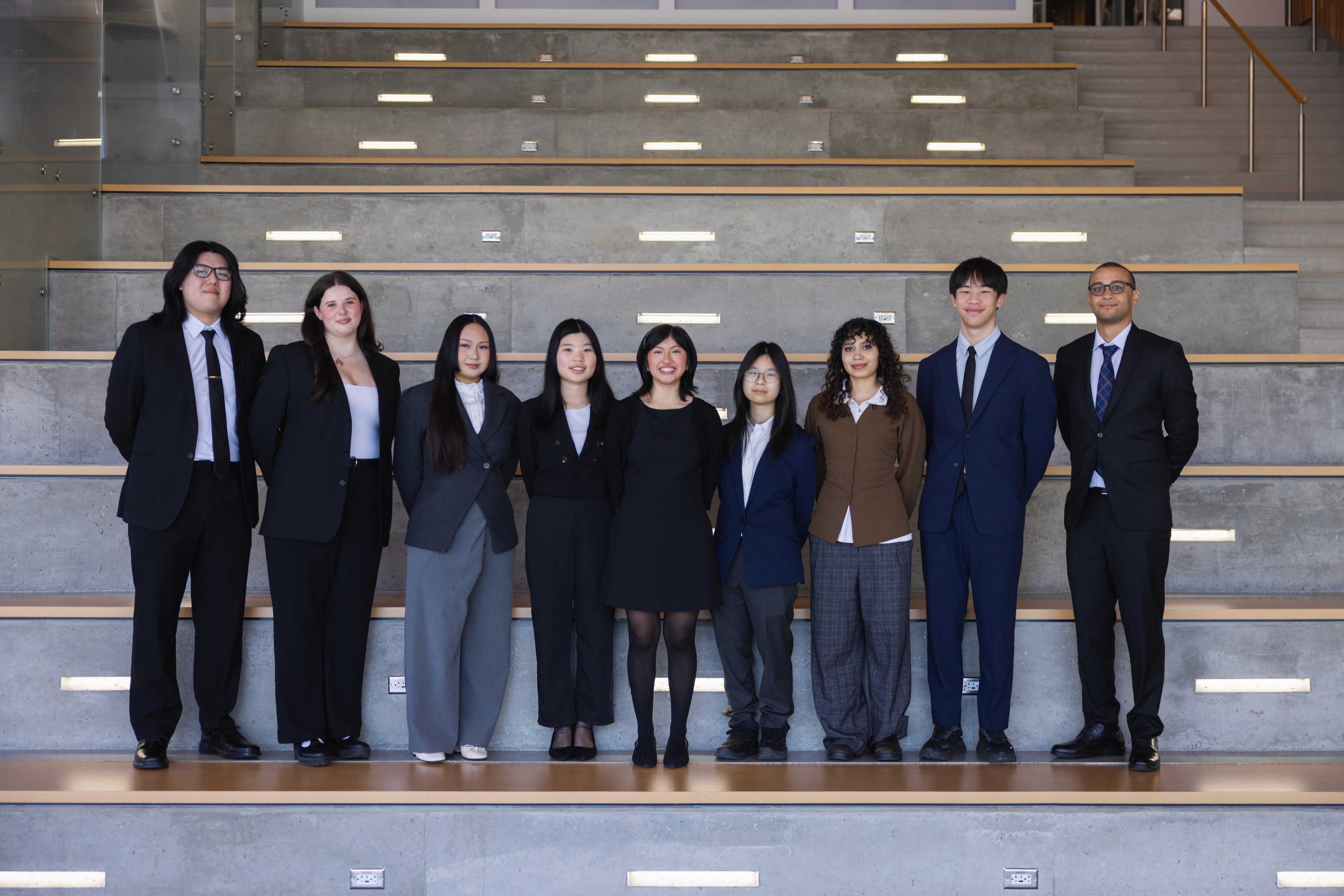 JDC West BCIT executive team in business attire standing on concrete steps