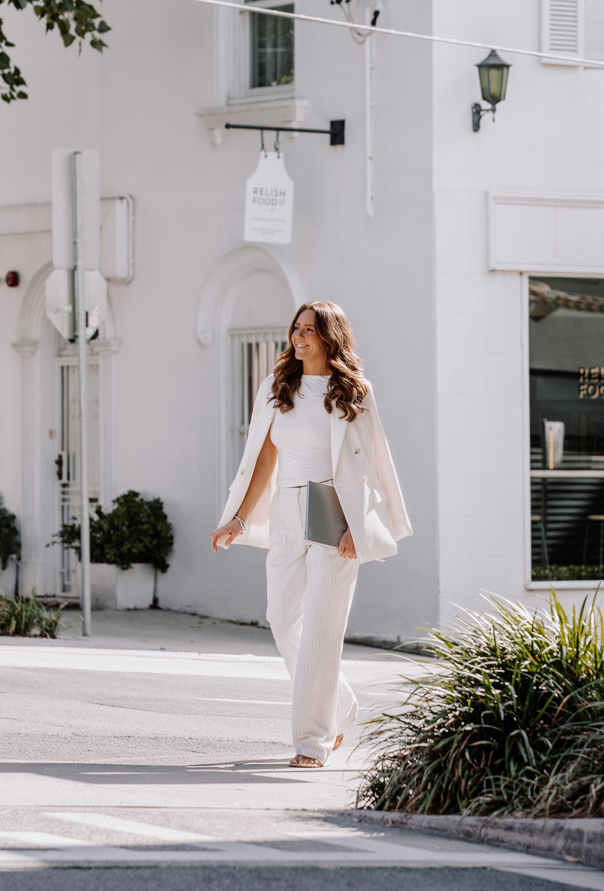Smiling woman walks a fluffy dog on a leash in a car park.