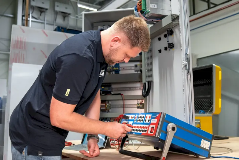 Ein Elektriker arbeitet an einem Schaltkasten mit Testgeräten.