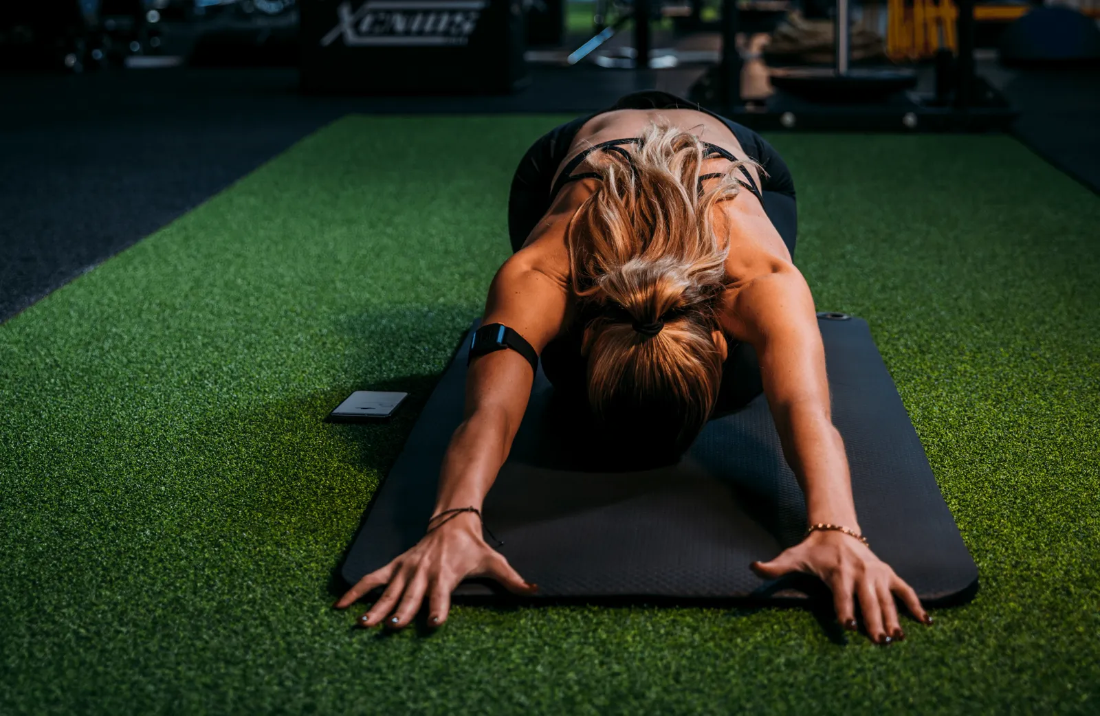 Socia che fa stretching su un tappetino con la fascia cardio ottica Uptivo Lightband