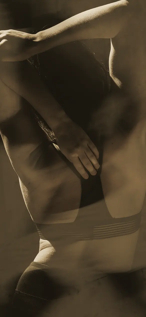 A sepia-toned close-up image of a person's midsection wearing minimal clothing, set in a dimly lit environment, suggesting themes of spa, wellness, and premium fitness.
