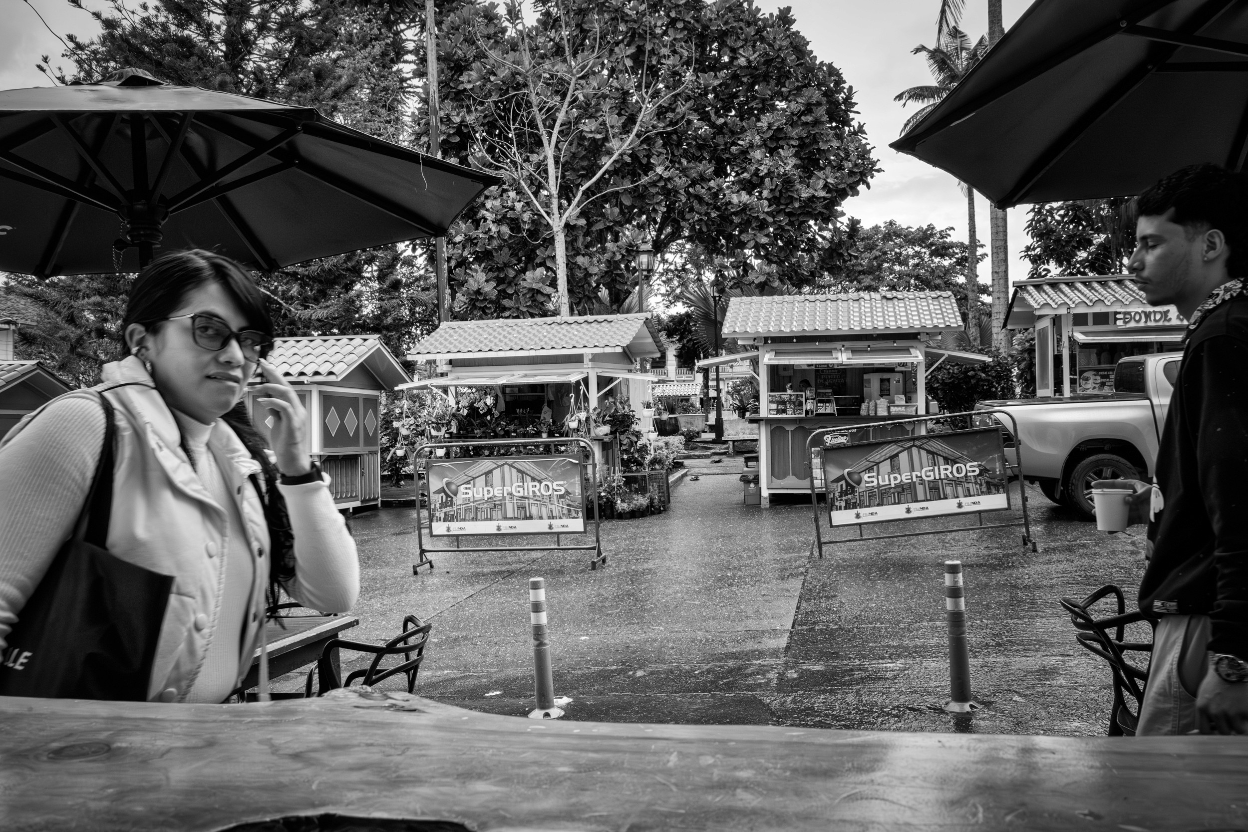 Rainy street scene with people passing by a bar window.