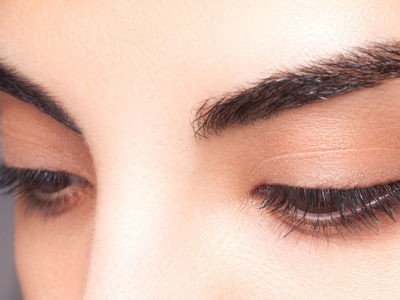a woman laying on top of a bed holding a hair dryer