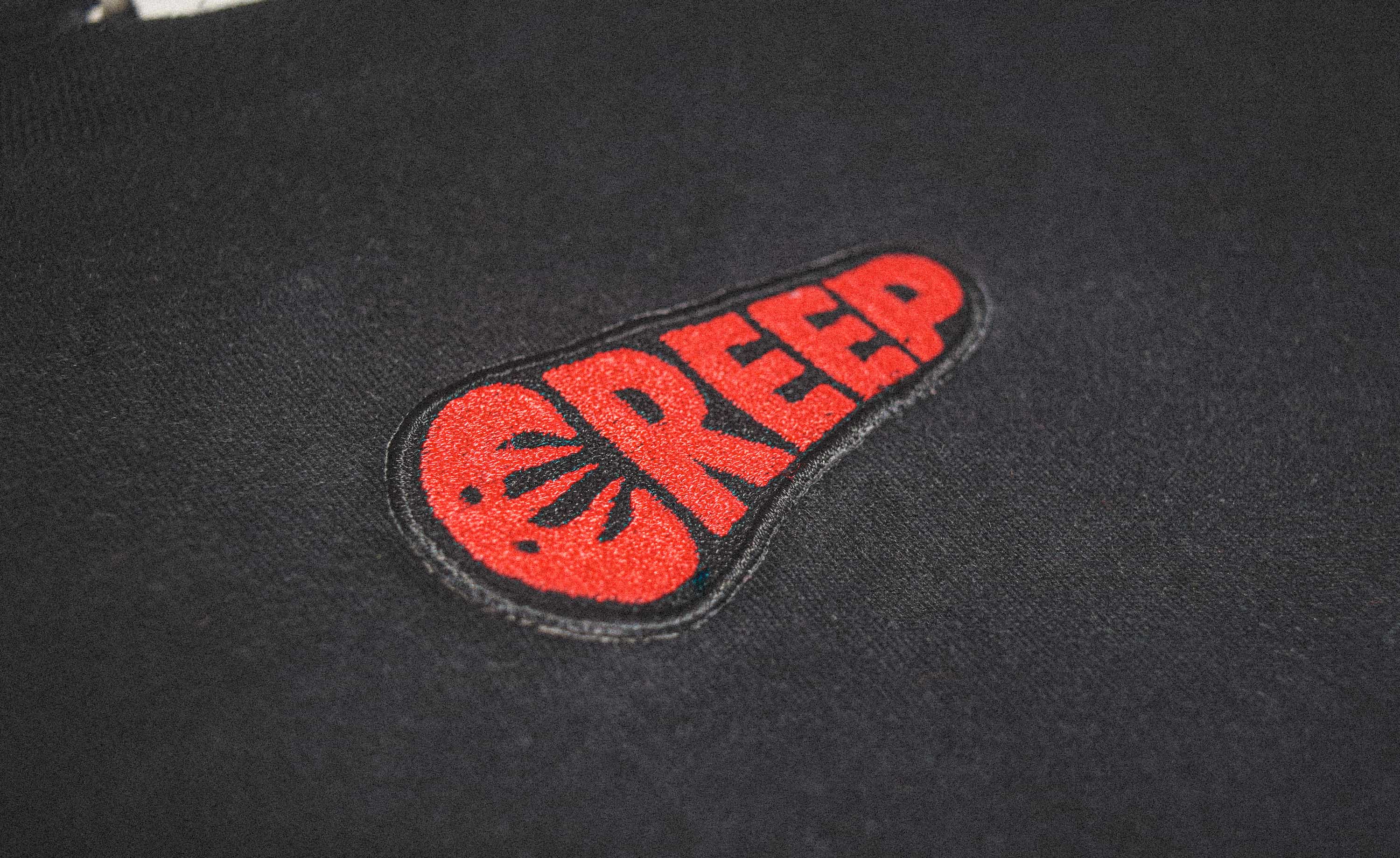 creep, embroidered word-mark on black t-shirt in red.