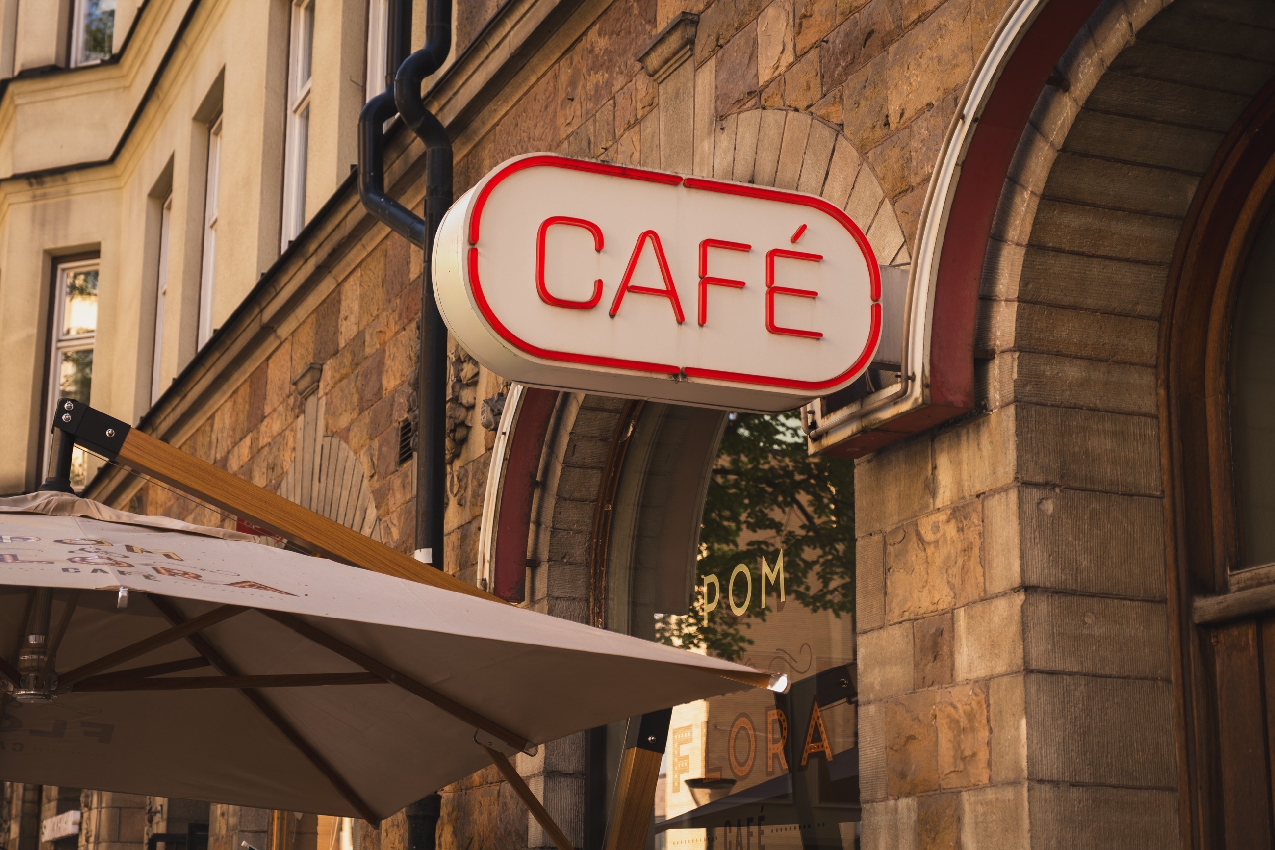 A red café sign against a warm stone façade
