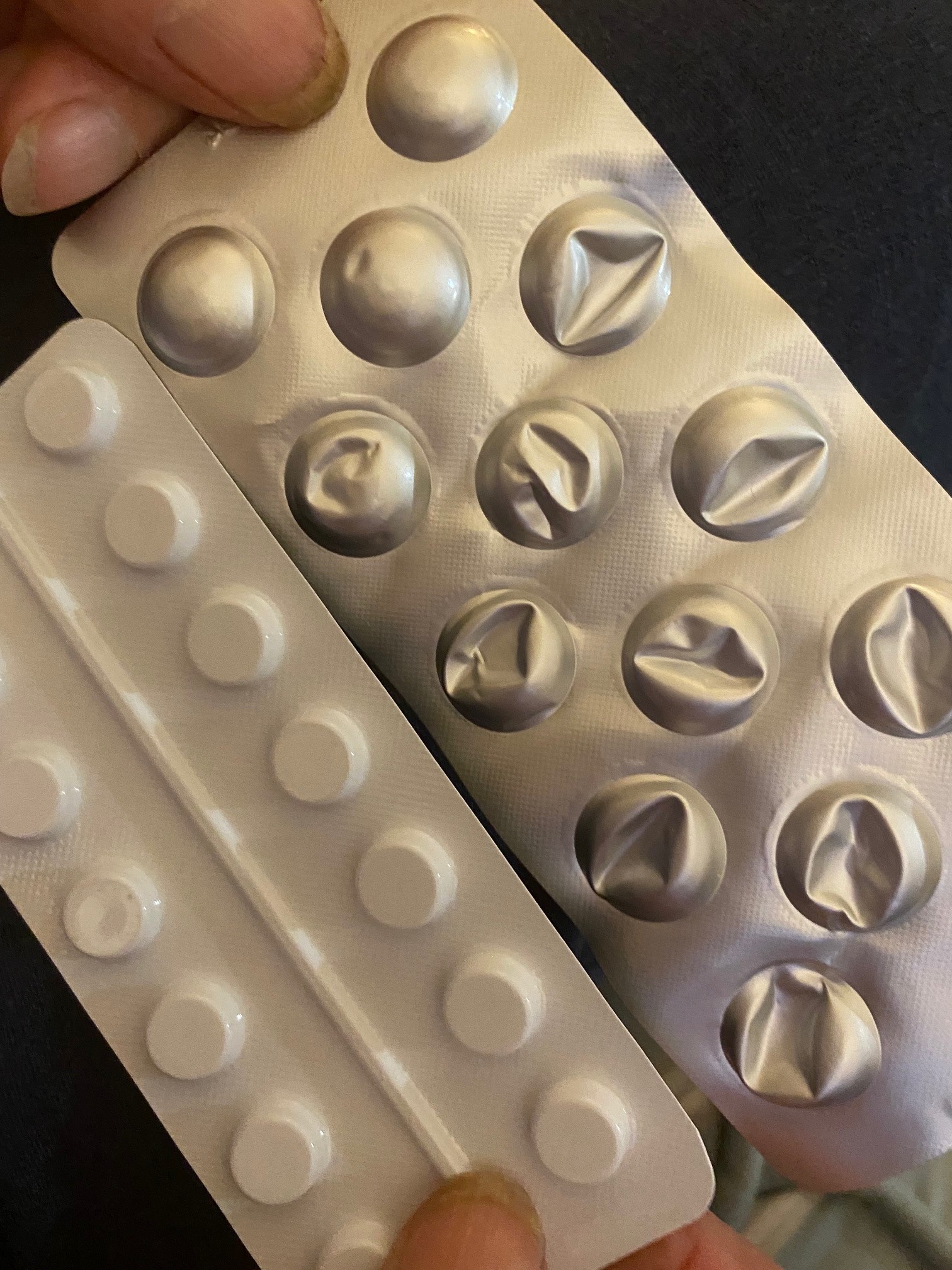 Elderly person comparing pill sizes.