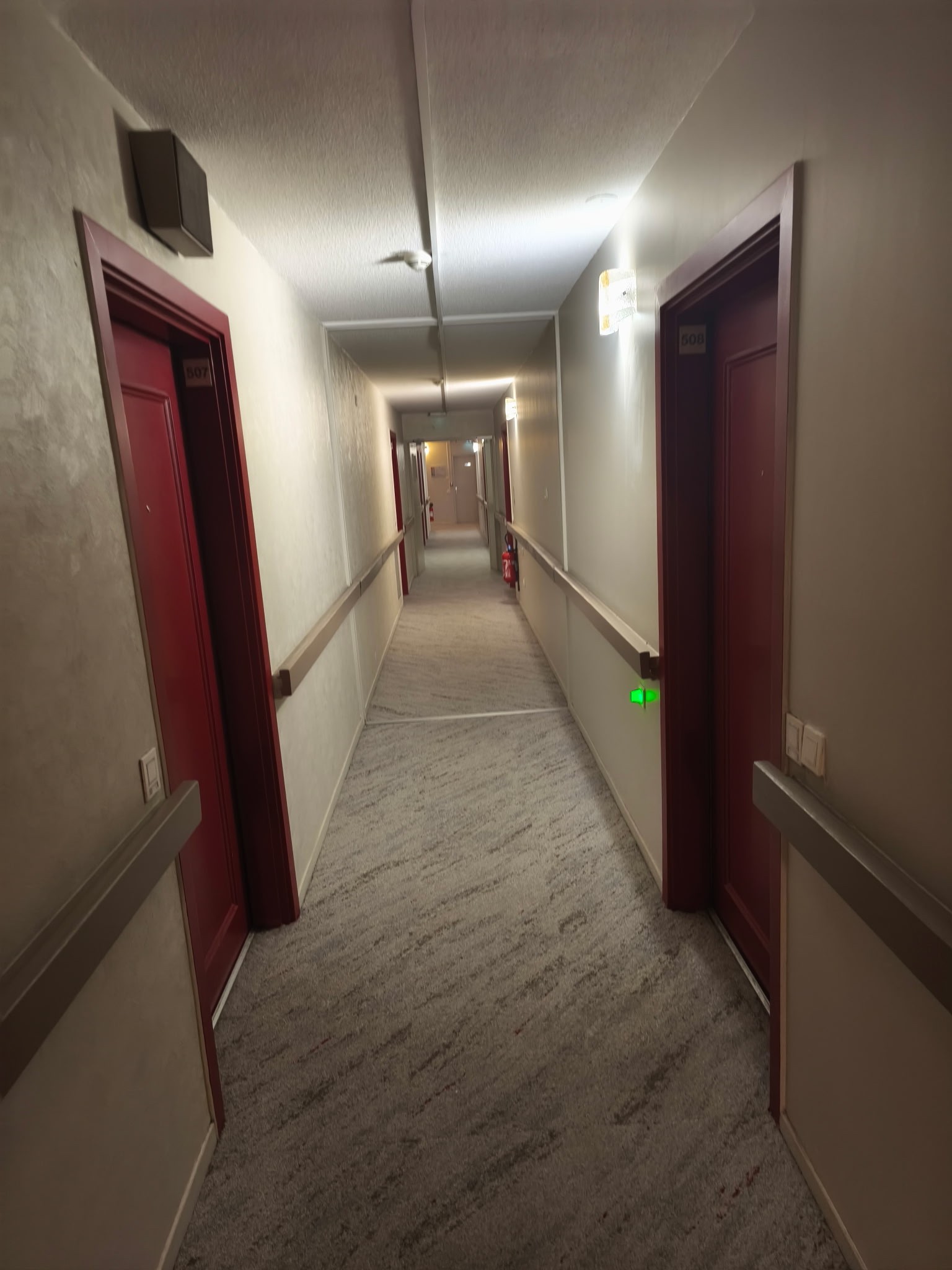 A smiling young man with crossed arms, wearing a plaid shirt and white t-shirt, poses against a dark background.