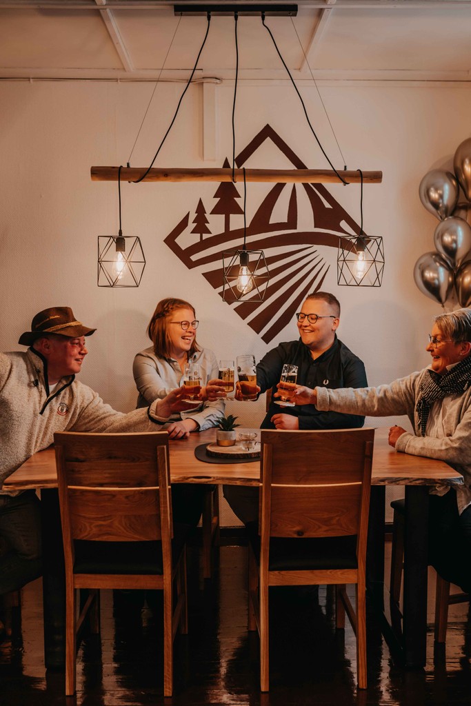 4 Personen die an einem Tisch anstoßen