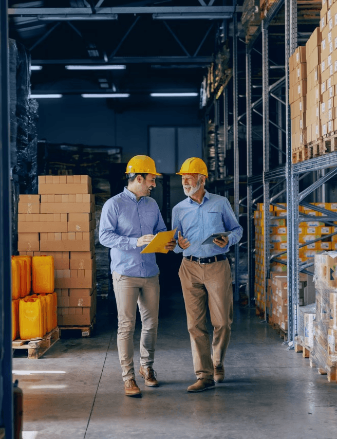 Two professionals in hard hats smiling and discussing logistics in a warehouse, representing Inway Risk Management’s client-focused approach to freight claims and supply chain solutions.