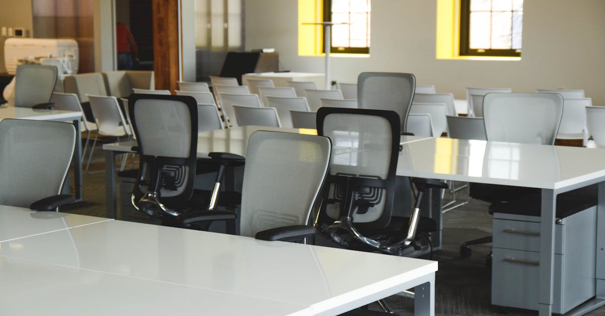 Spacious open office workspace with desks, chairs, and natural lighting.