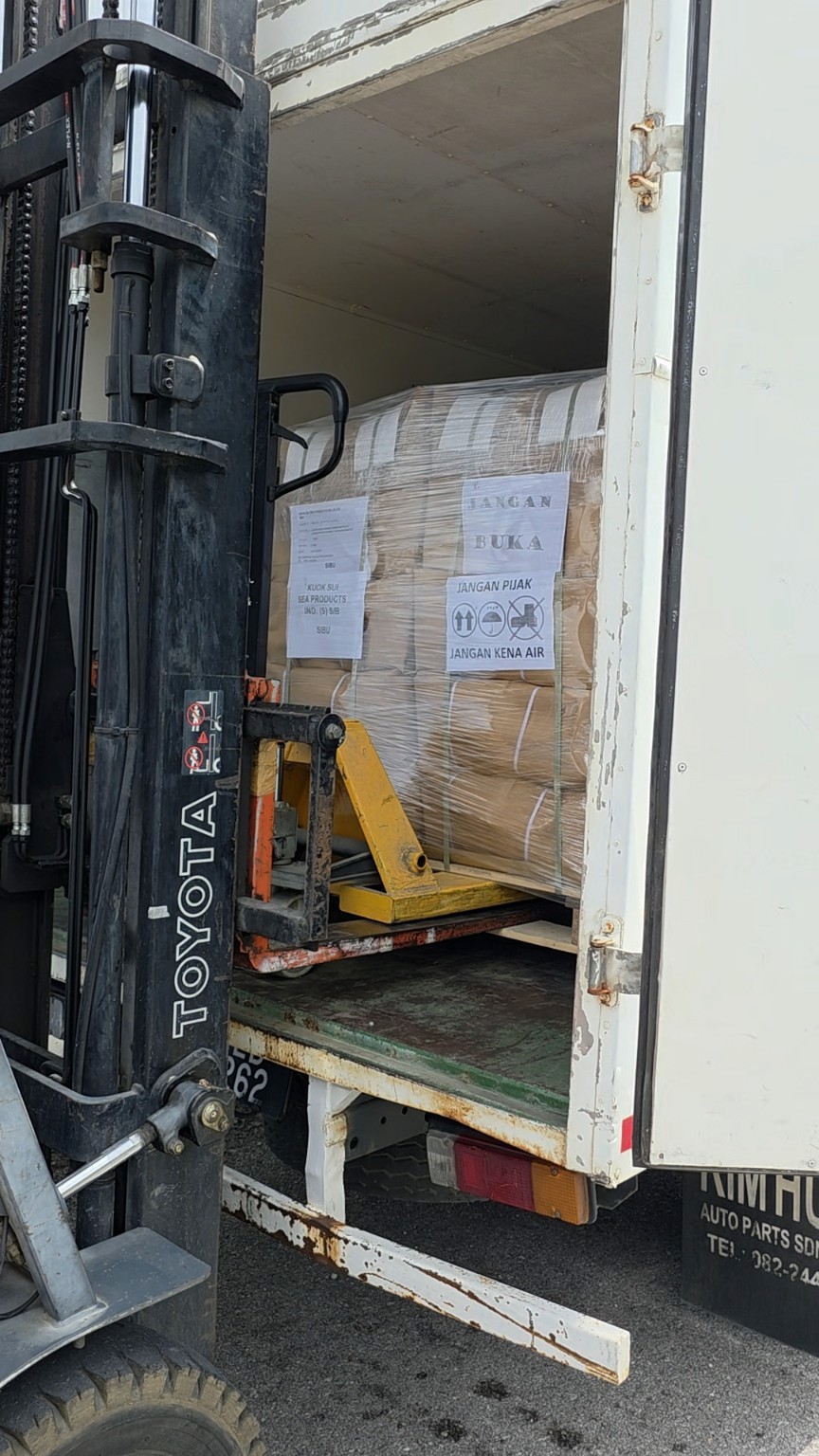 Loading flat-packed wholesale cake boxes into delivery lorry for daily shipping to Sibu, Miri, Bintulu and Sabah.