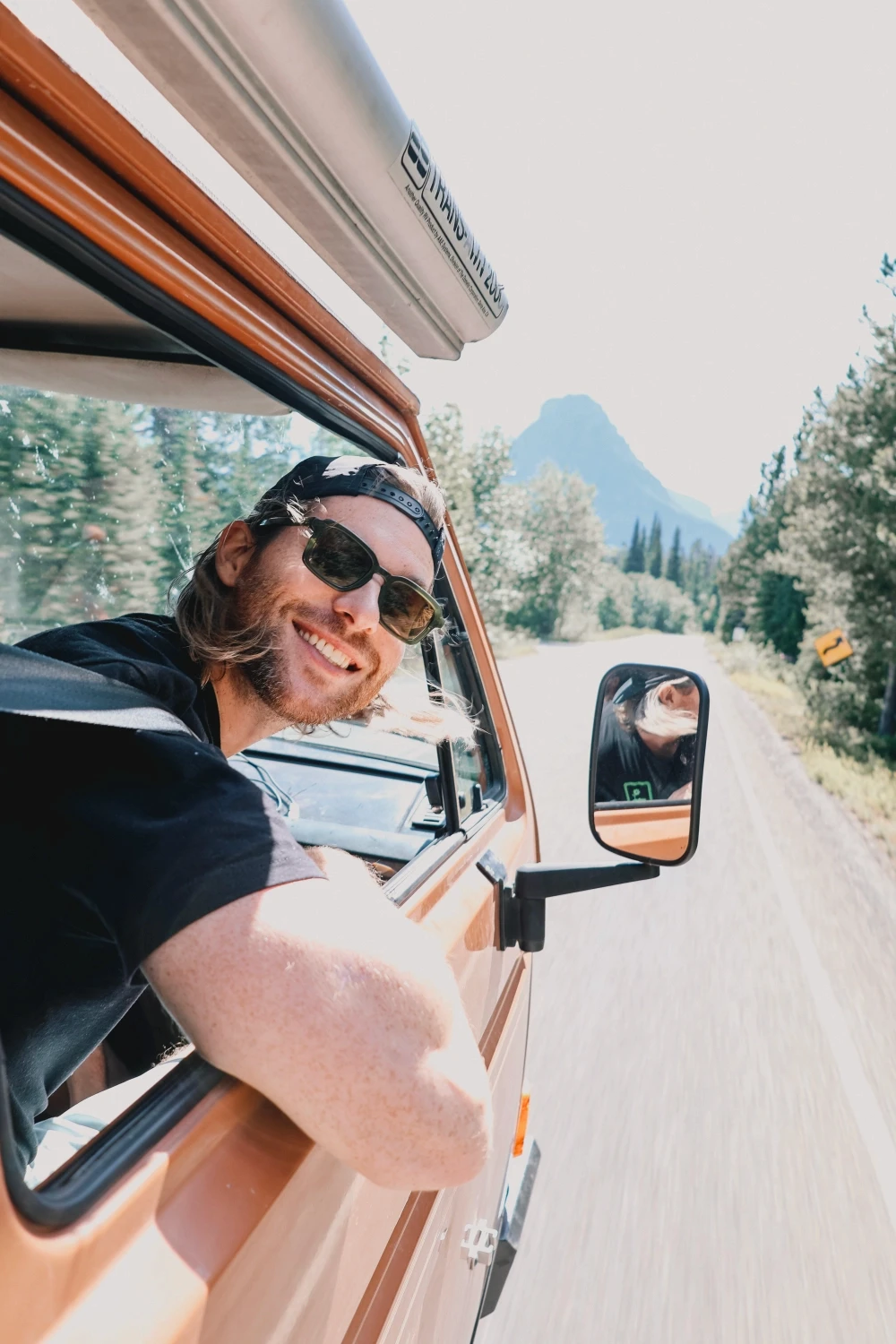 Person wearing a blue puffer jacket and red backpack standing in front of a light blue building on a city street.