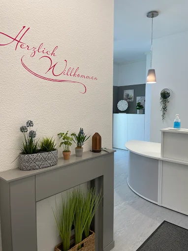 Der Eingang der Naturheilpraxis mit Herzlich Willkommen Schild und Pflanzen