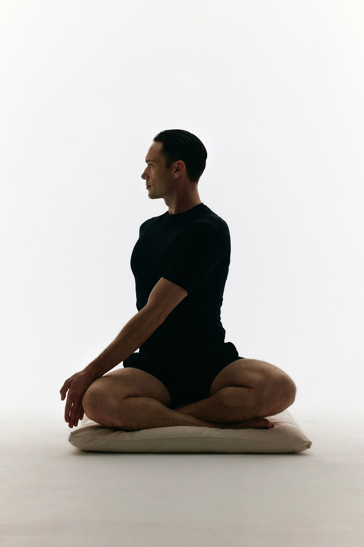 A man in a yoga pose wearing a black outfit.
