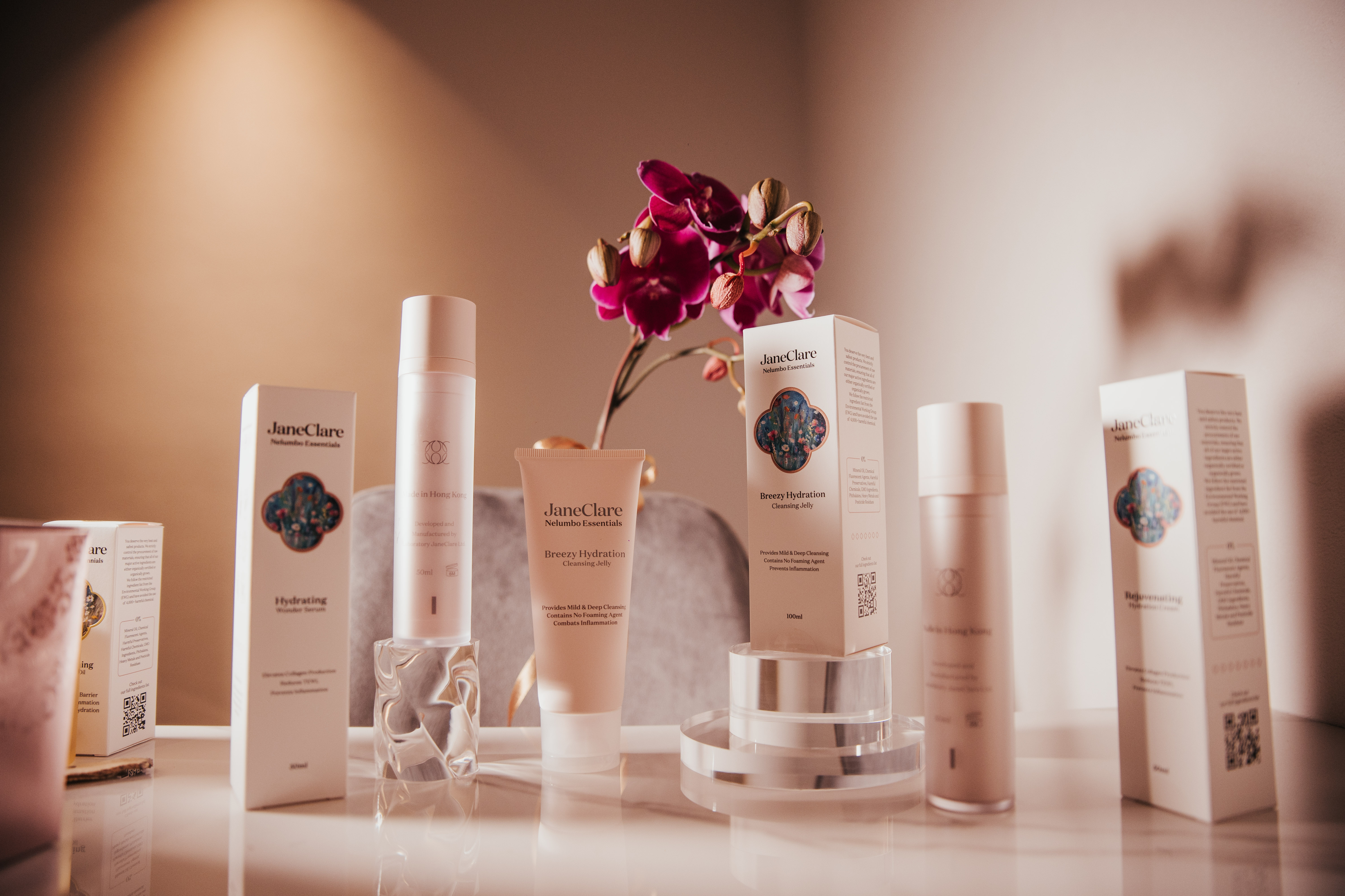 A commercial photography setup showcasing the full range of JaneClare skincare products in neutral tones.
