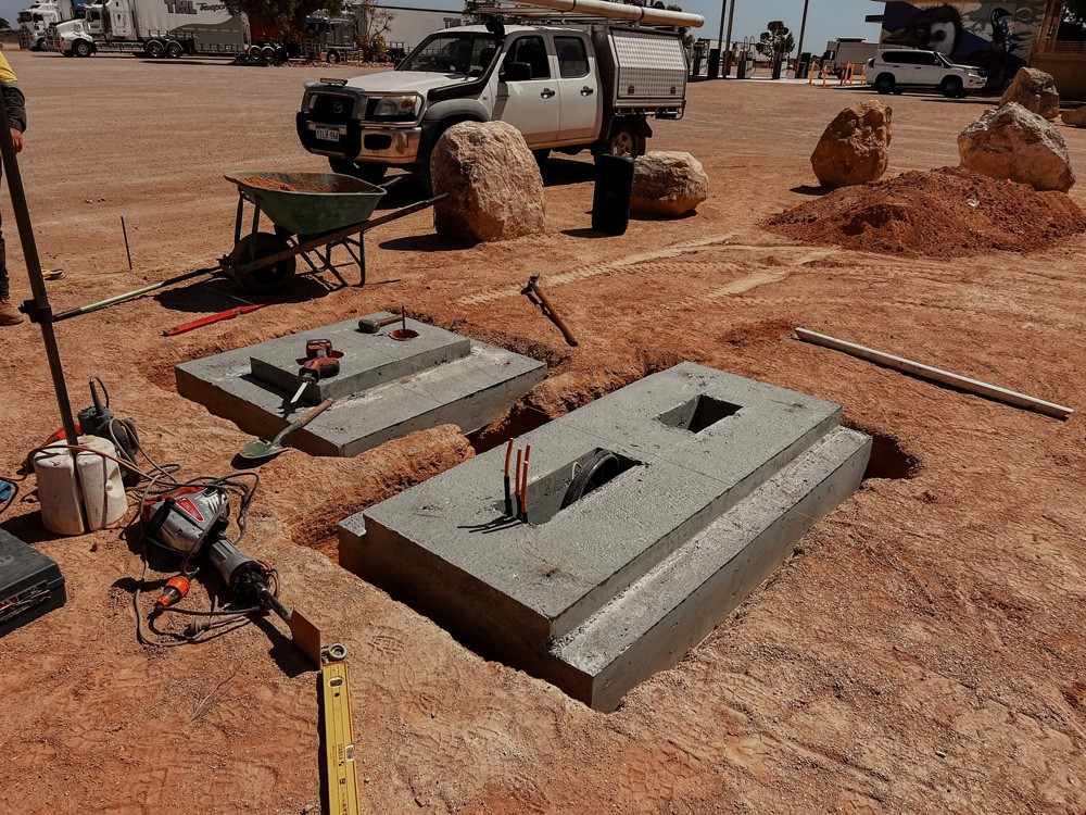 Construction of concrete foundations for renewable energy systems in remote Australian industrial site with tools and machinery.