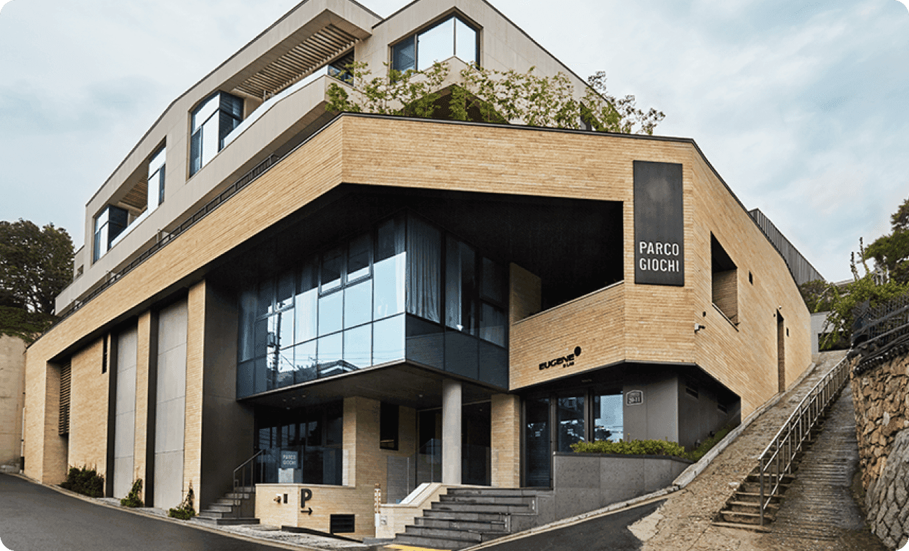 A modern architectural building with a mix of stone and glass, featuring multiple levels and greenery on the roof.