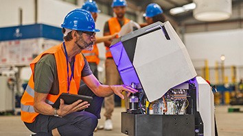 Worker examining a robot for SRI robot teams story