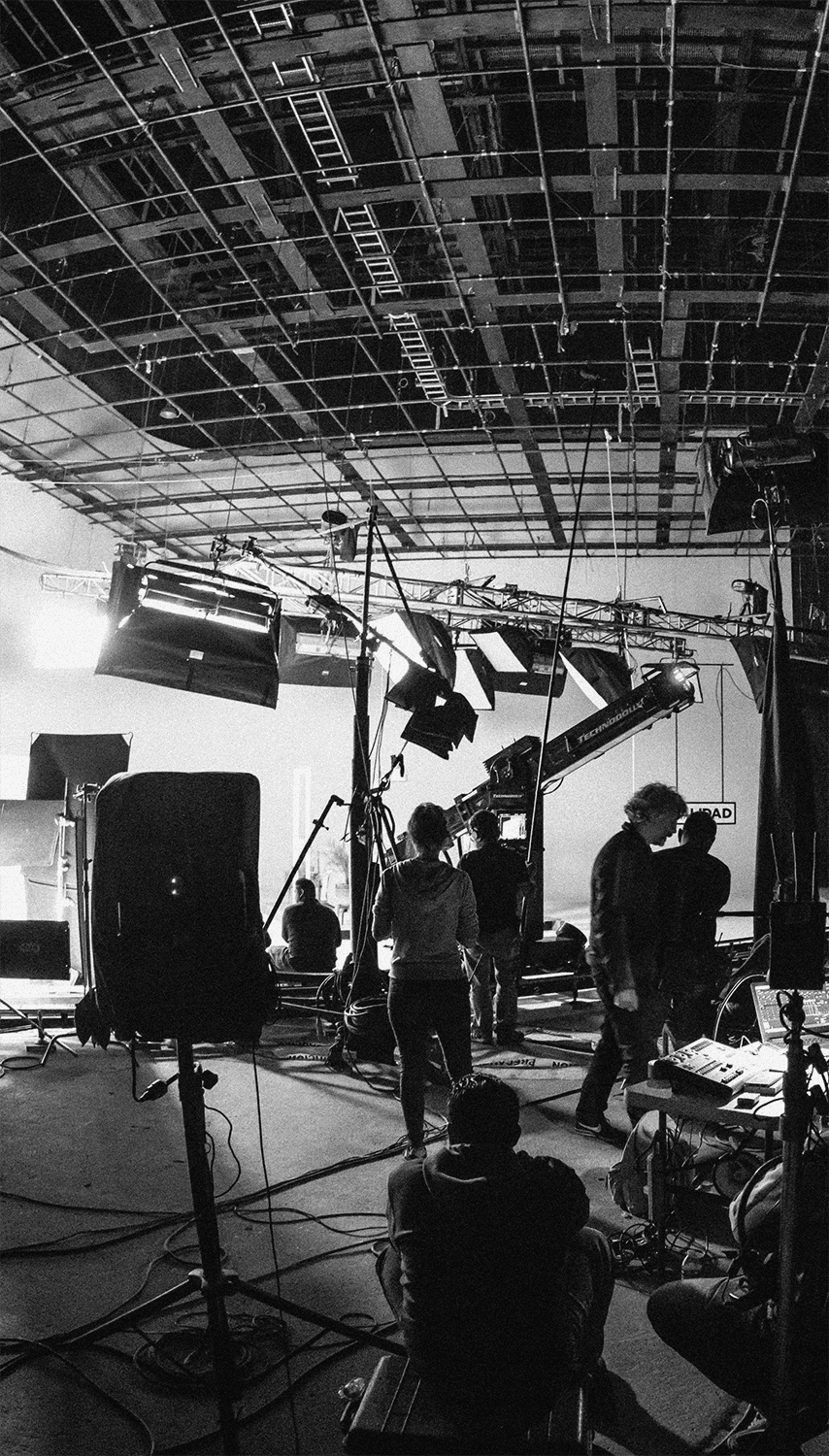 Scientist wearing safety goggles and blue lab attire, using a pipette to transfer liquid into a vial in a laboratory setting.
