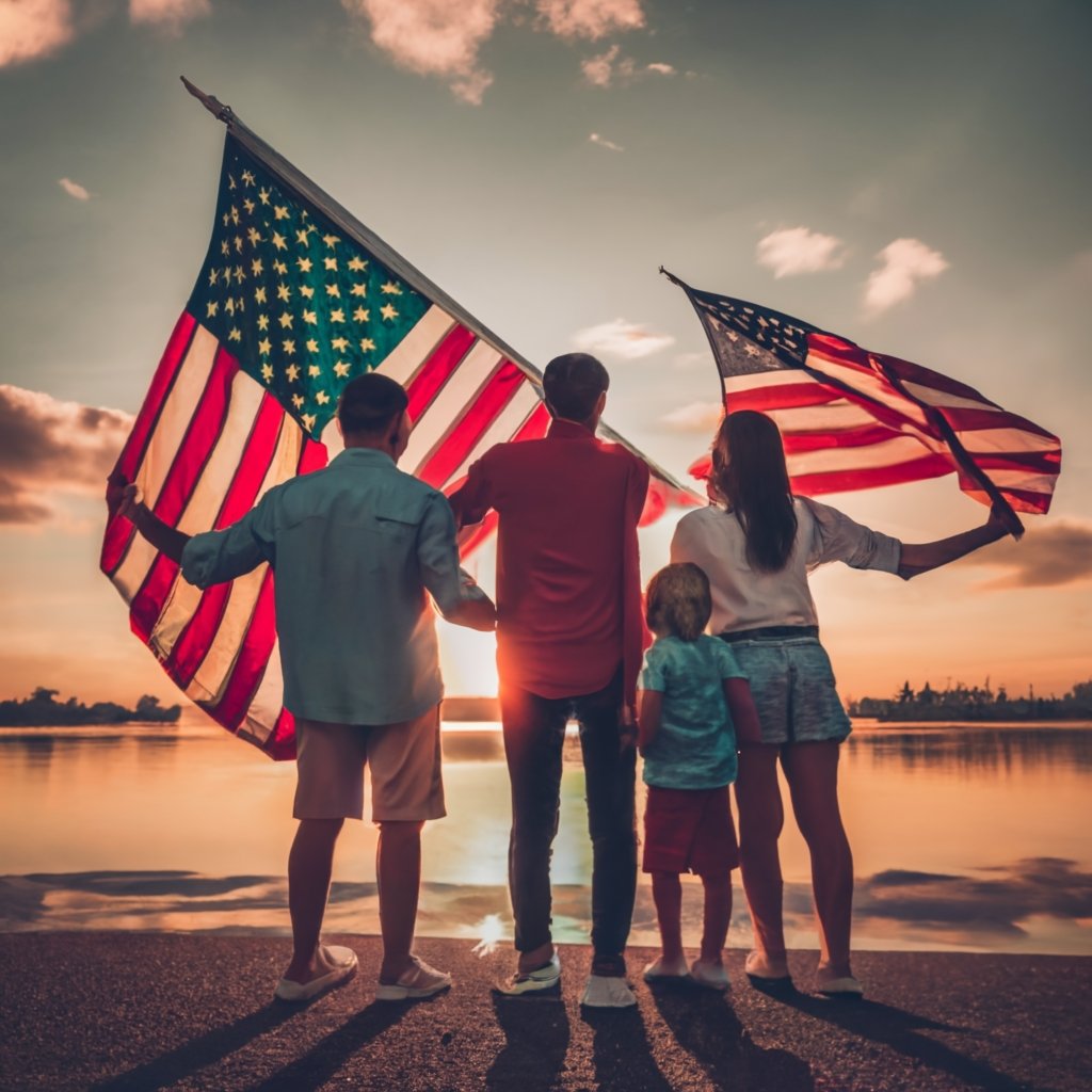A family standing together holding U.S. flags, symbolizing the reunification that Form I-130 can facilitate.