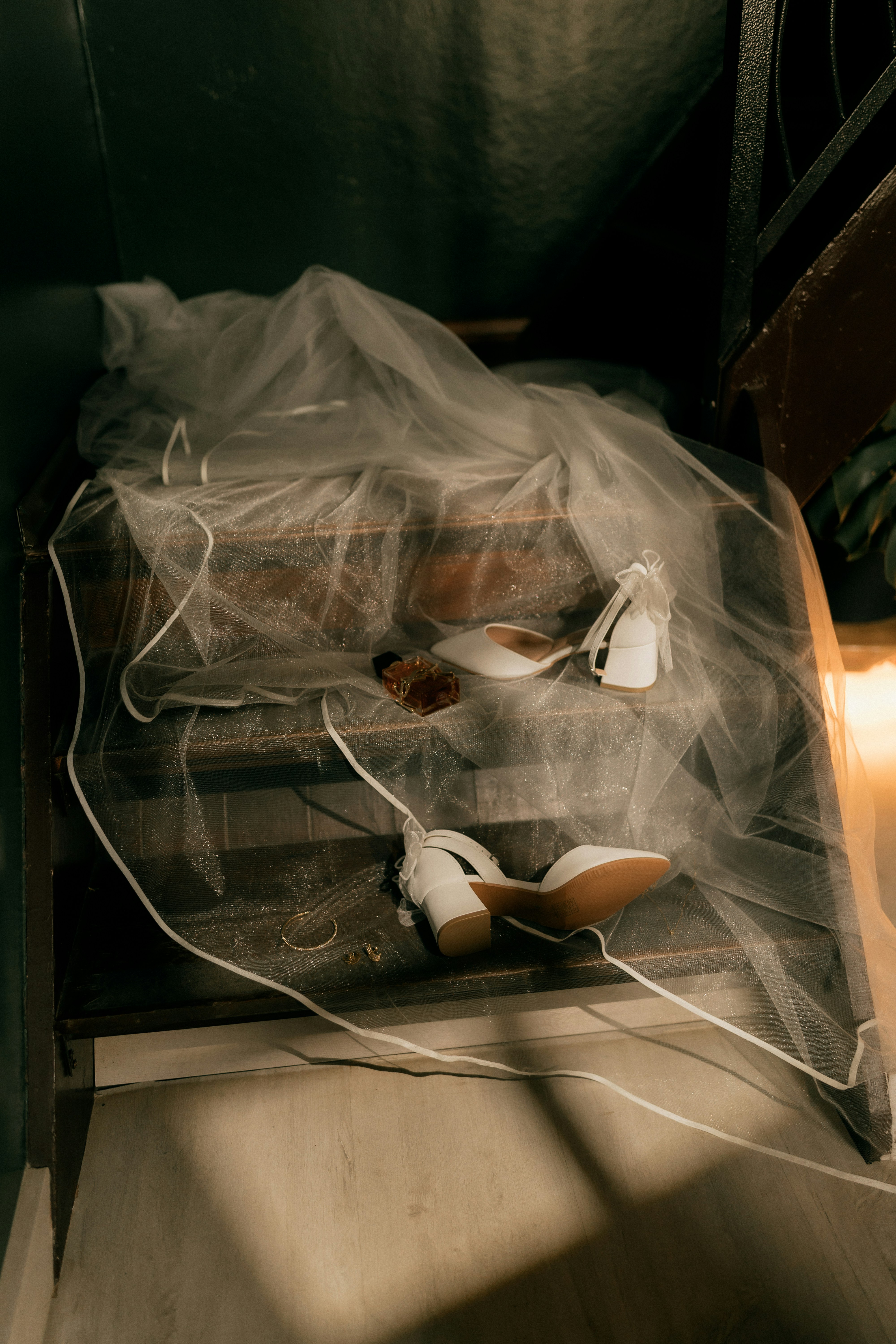 White wedding shoes and veil on a wooden dresser.