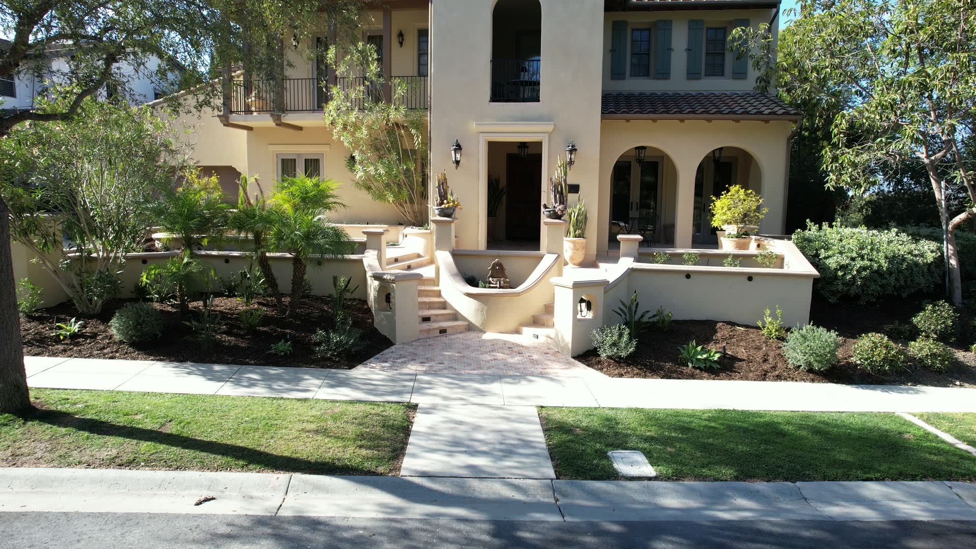 Interlocking-paver entry courtyard leading to curved steps and a landscaped home.