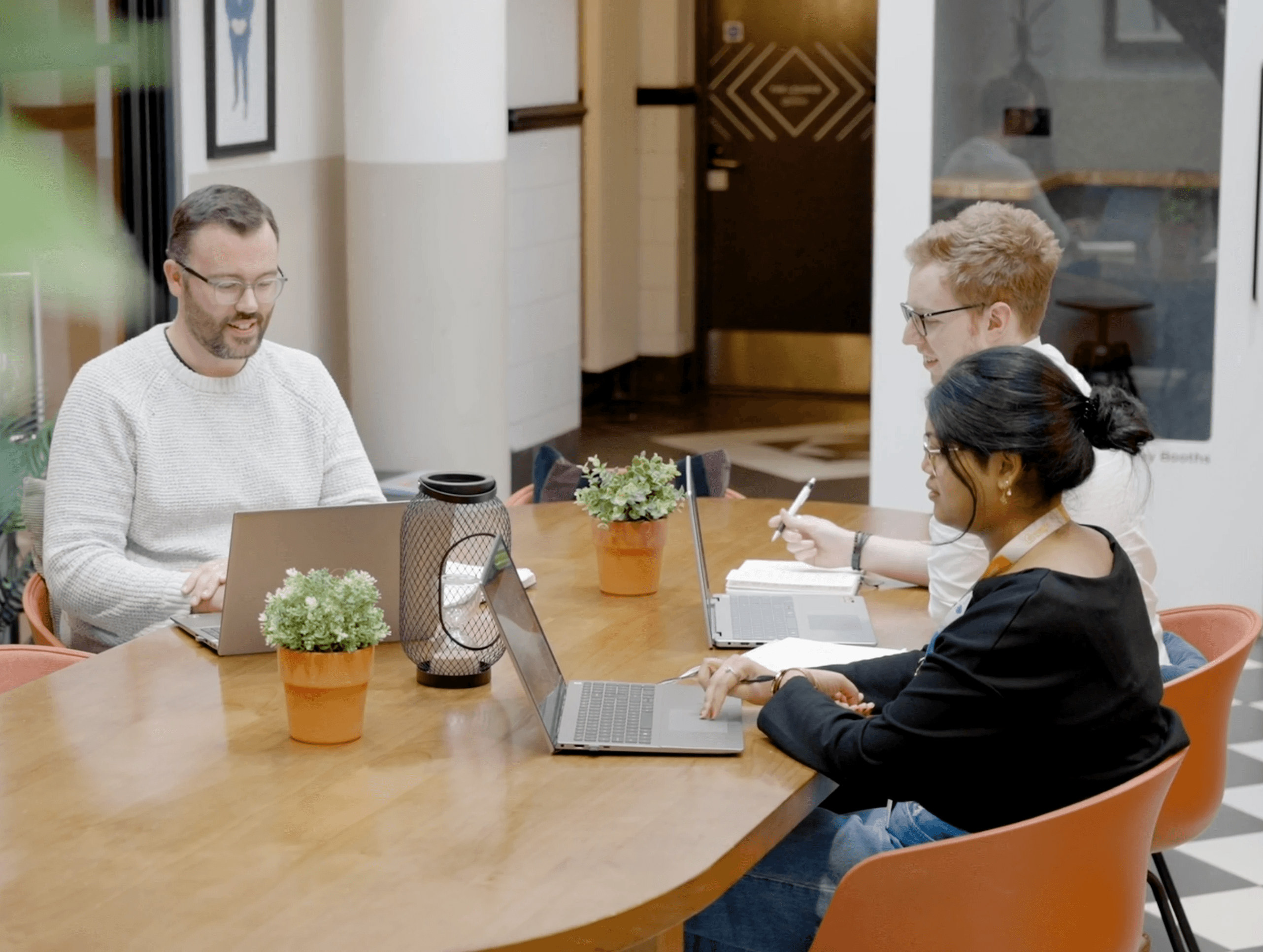 The Tiedot team collaborating around a table with laptops during a meeting