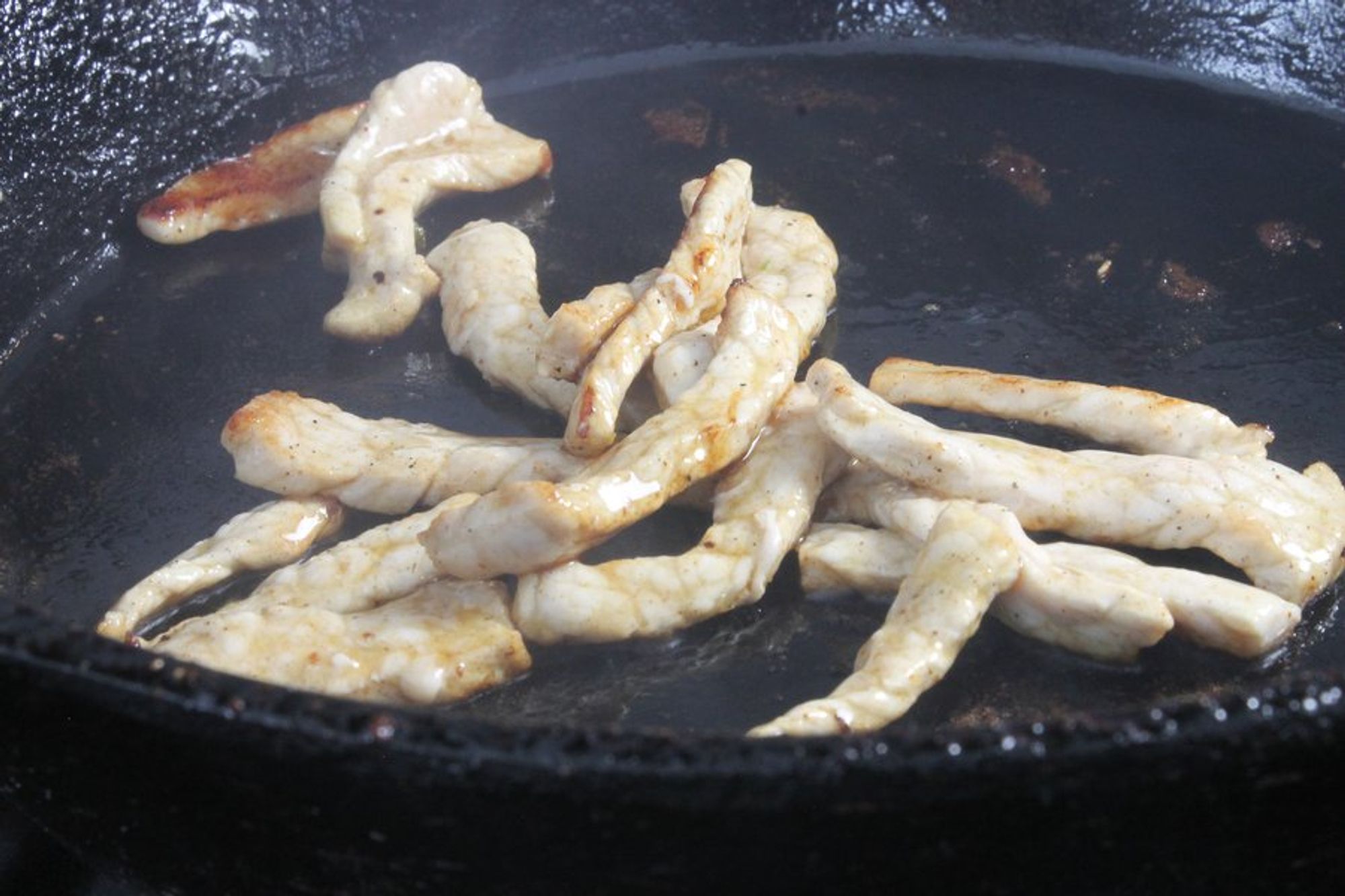 pork tenderloin being cooked on a skillet