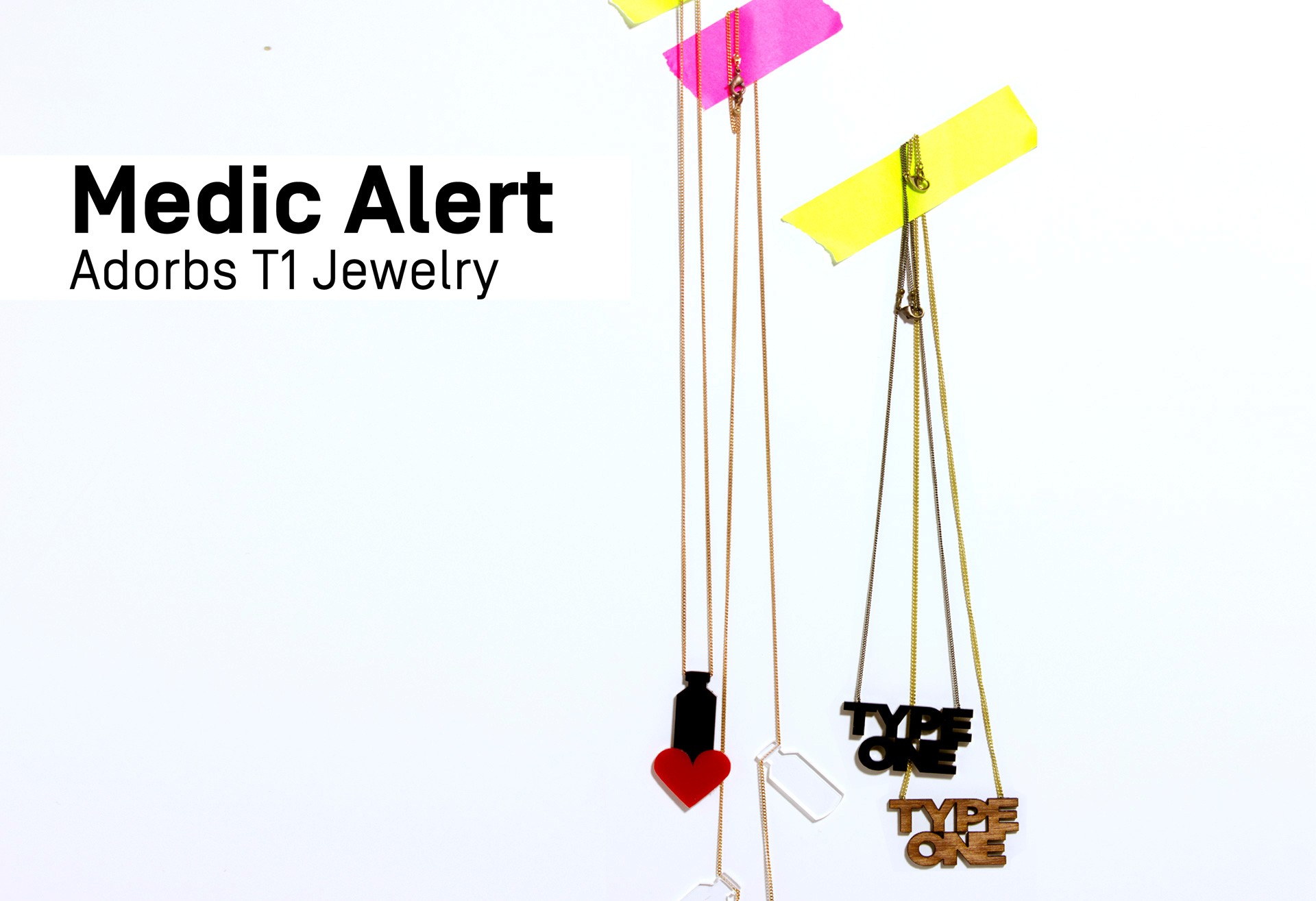 The image displays several necklaces hanging against a white background. Each necklace has a thin chain and a pendant hanging from it. The pendants vary in color and design, including black, red, white, and brown. One pendant is shaped like a heart, another resembles a bottle, and a third is shaped like the words “TYPE ONE”. Two yellow rectangular strips are attached to the top of the image. The text “Medic Alert” and “Adorbs T1 Jewelry” is visible in the top left corner.